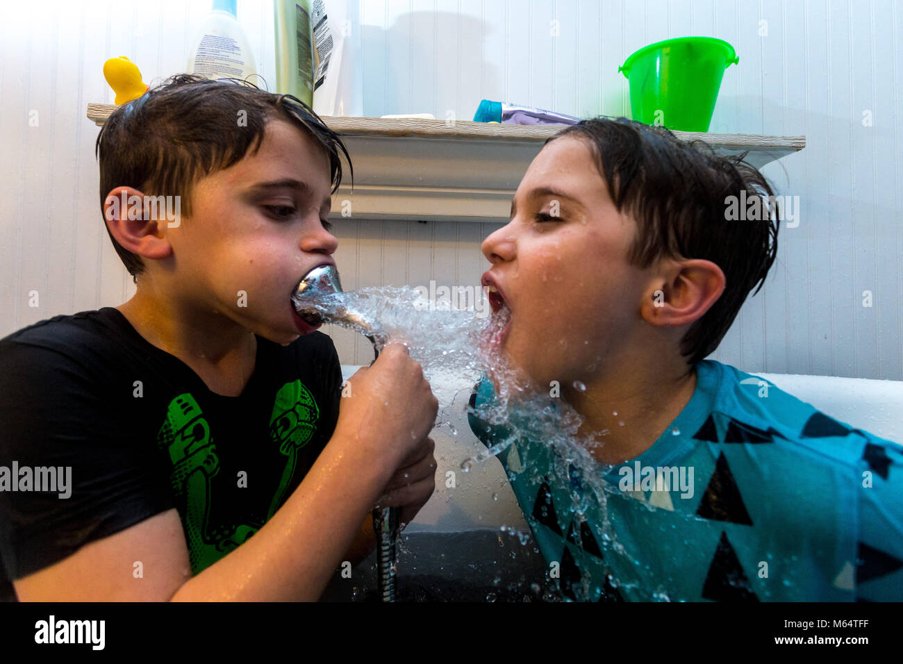 Twin kaukasischen Brüder spielen in Ihrer Wasser gefüllten Badewanne zusammen mit ihrer Kleidung an Stockfoto
