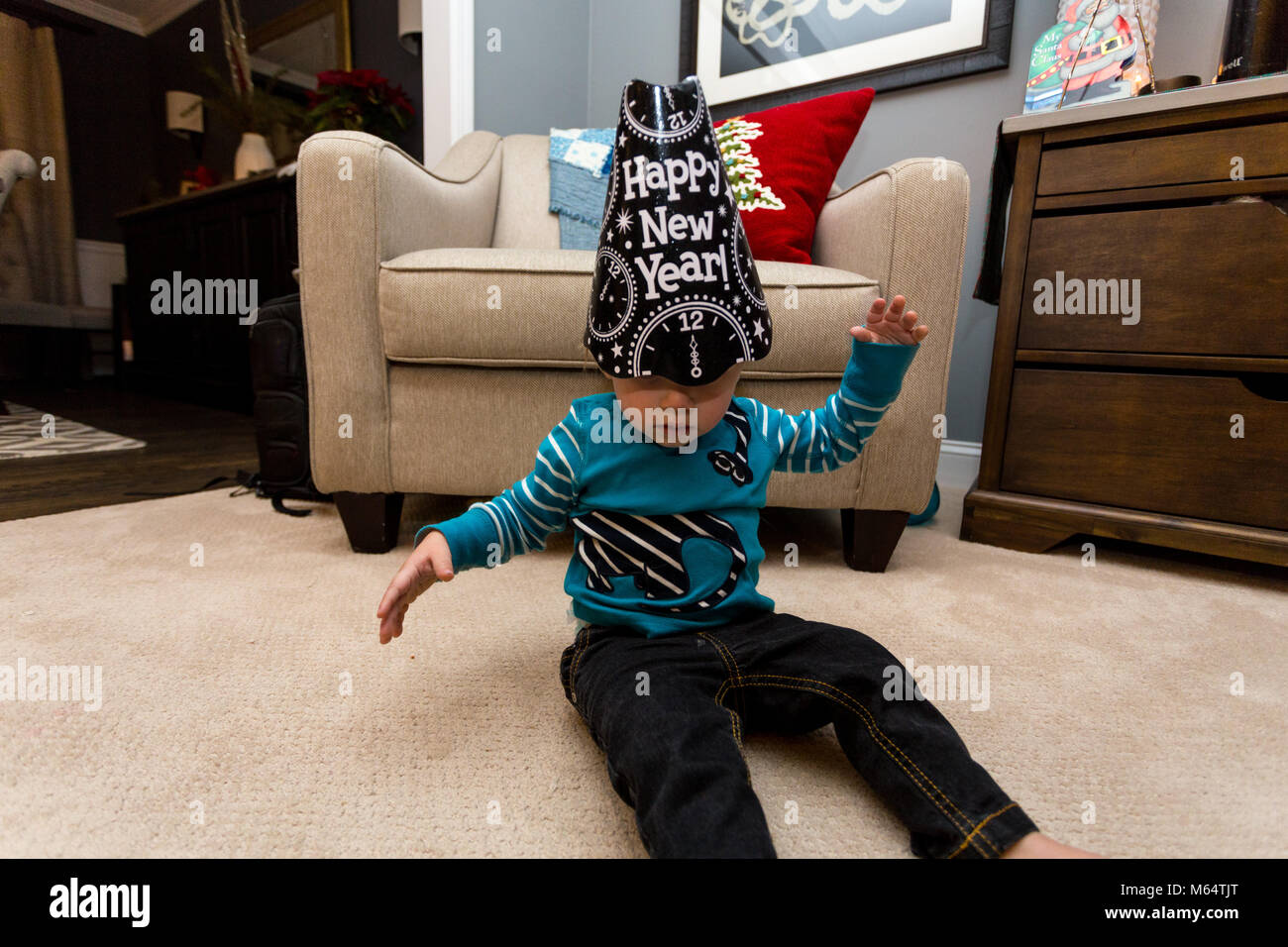 Ein kaukasischer Junge trägt ein Glückliches Neues Jahr hat in seinem Vorstadthaus Wohnzimmer Stockfoto