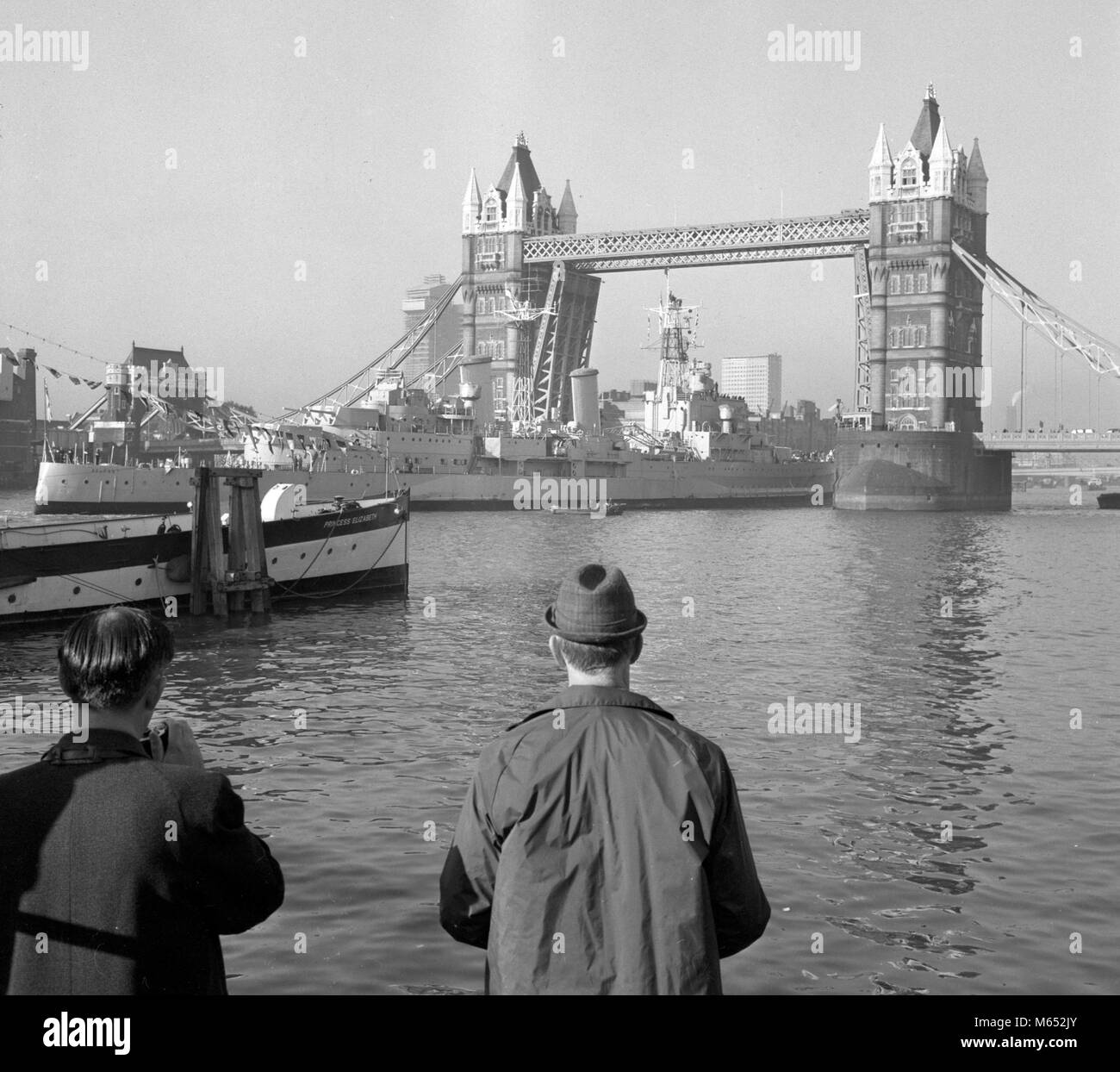 HMS Belfast, der Letzte der Royal Navy's Big-gun Kreuzer, durch die Tower Bridge auf dem Weg von der King George V Dock in Greenwich zu ihrer endgültigen Liegeplatz in der Nähe von Tower Bridge, wo Sie ein schwimmendes Museum geworden. Stockfoto