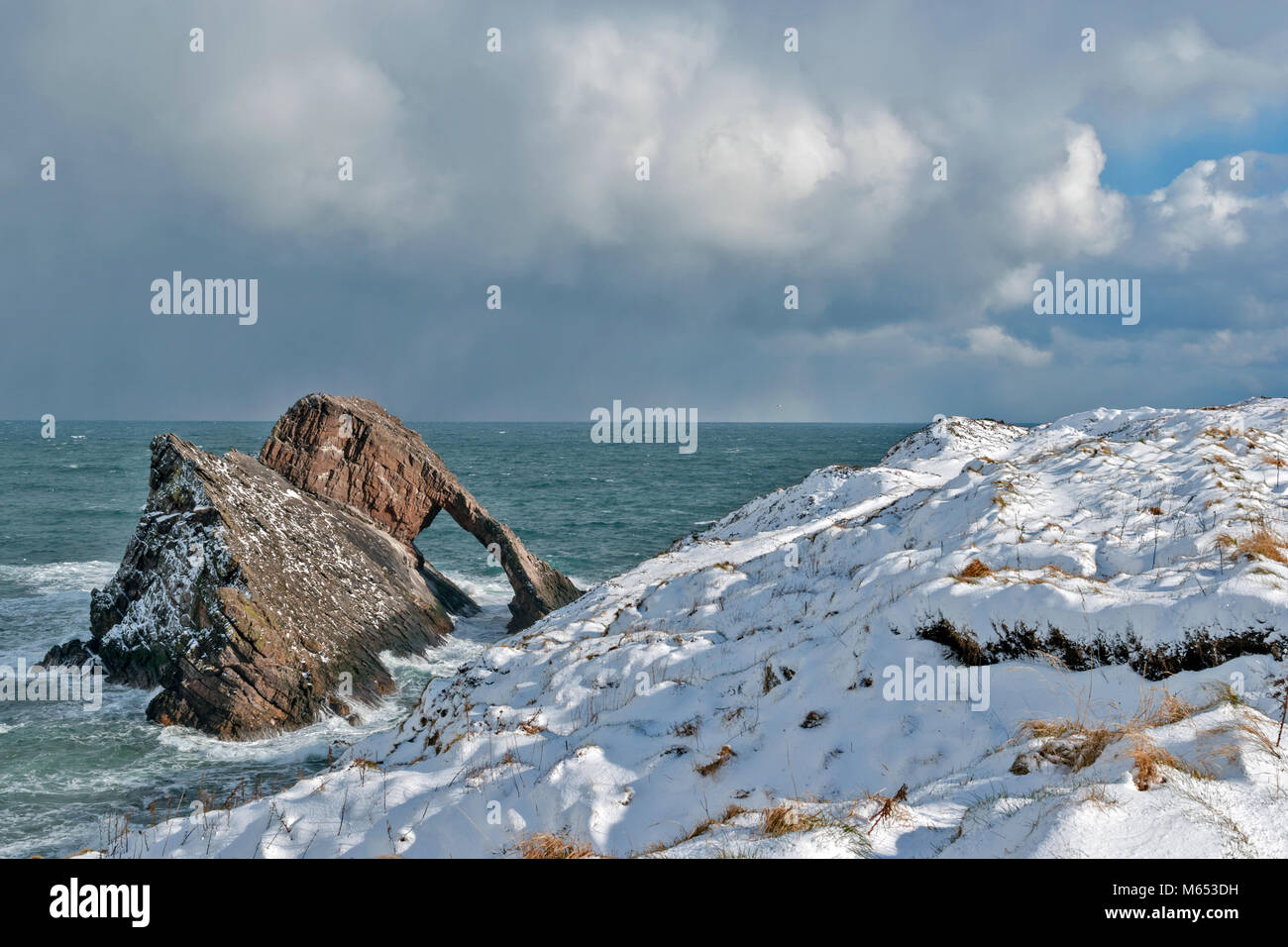 Küste von Moray in Schottland PORTKNOCKIE BOGEN GEIGE ROCK IM FEBRUAR WINTER MIT STARKEM WIND UND SCHNEE Stockfoto