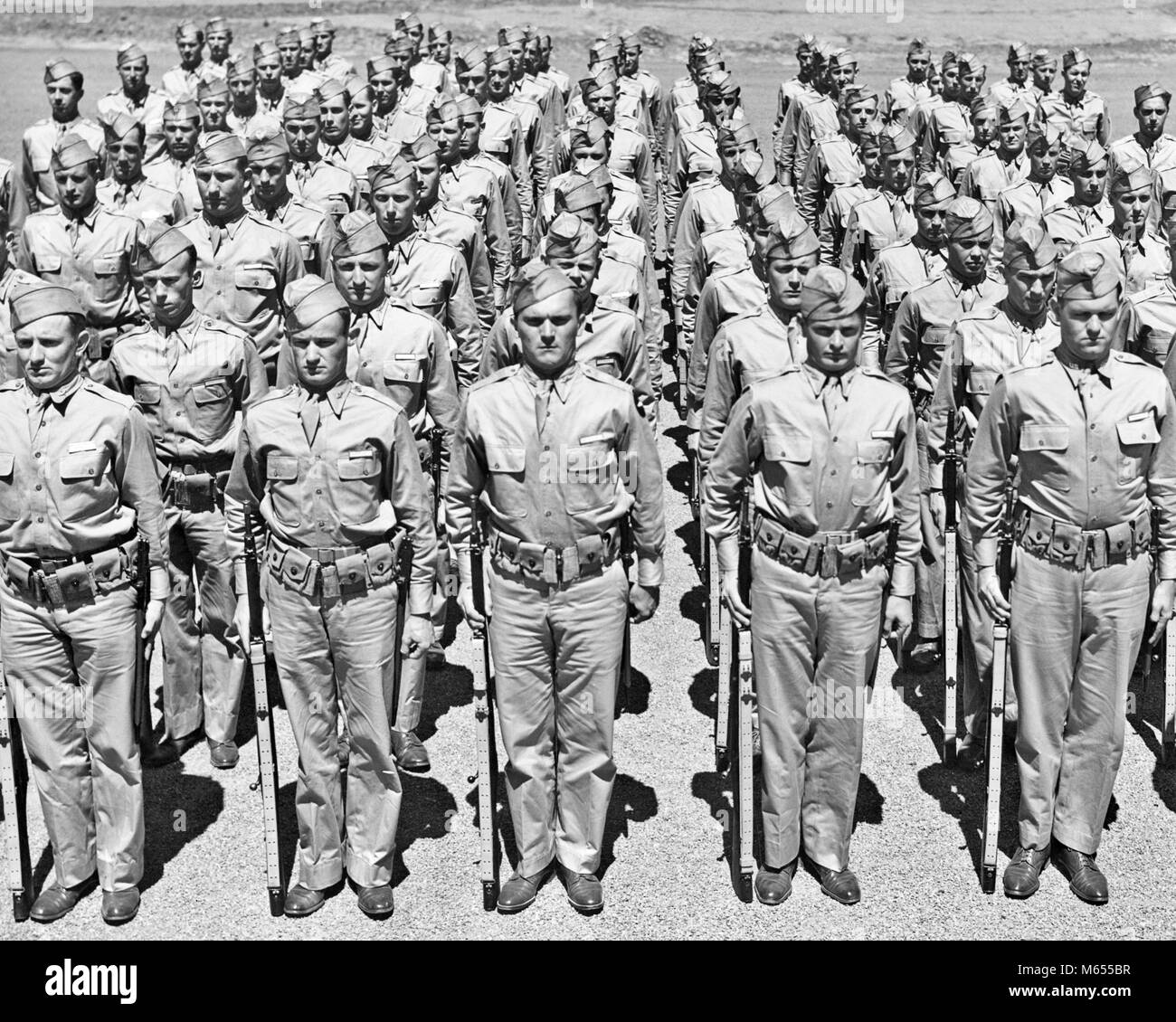 1940 ZEILEN DES AMERIKANISCHEN WELTKRIEGSOLDATEN STEHEND AN AUFMERKSAMKEIT MIT GEWEHREN AUF KAMERA-a 2433 HAR 001 HARS WELTKRIEG WELTKRIEG ZWEI BILDUNG ZEILEN TRUPPEN UNIFORMEN GEWEHRE GROSSE GRUPPE VON MENSCHEN FEUERWAFFE FEUERWAFFEN KHAKI MÄNNER MITTE erwachsenen Mann Waffen junger Erwachsener MAN B&W SCHWARZ UND WEISS KAUKASISCHEN ETHNIE AUF KAMERA BERUFE ALTMODISCHE PERSONEN RANG RANG UND DATEI REKRUTEN REGIMENT STEHEND AN Stockfoto