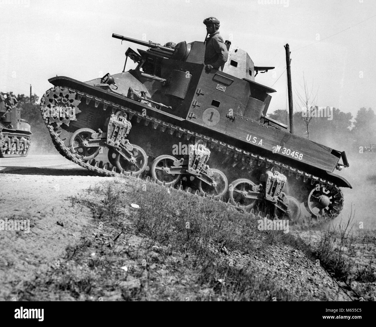 1930er Jahre 1940er Jahre kleine amerikanische Armee M2 LIGHT TANK AUF EINER STEIGUNG VON SEITE DER STRASSE - ein 2434 HAR 001 HARS AUFREGUNG WELTKRIEGE INNOVATION WELTKRIEG WELTKRIEG ZWEI MOTION BLUR MOBILITÄT FEUERWAFFE FEUERWAFFEN M2 All Terrain Armored ATV B&W SCHWARZ UND WEISS NEIGUNG LIGHT TANK ALTMODISCH vor dem Krieg verfolgt Stockfoto