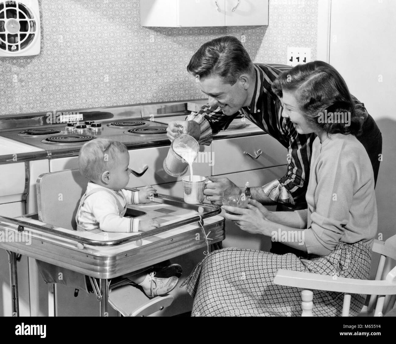 1950 s Vater GIESSEN MILCH IN DIE TASSE FÜR SOHN IM HOCHSTUHL MIT MUTTER sitzt an der Seite - b 1906 HAR 001 HARS SCHALE BABYS MAMA KLEIDUNG STRESS NOSTALGISCHE GIESSEN PAAR STILVOLLE SUBURBAN MÜTTER ALTE ZEIT ZUKUNFT ALTE MODE 1 FÜTTERUNG JUGENDLICHER STIL SICHERHEIT TEAMARBEIT KAUKASISCHEN GERNE FREUDE LIFESTYLE FEIER FRAUEN VERHEIRATET EHEPARTNER EHEMÄNNER GESUNDHEIT LEBEN ZU HAUSE SITZEN PLATZ KOPIEREN, halbe Länge DAMEN FITNESS INTERESSIEREN PAARE IM INNENBEREICH VERTRAUEN NOSTALGIE VÄTER MITEINANDER 1-2 Jahre 25-30 JAHRE ERFOLG FRAUEN GLÜCK WELLNESS MAMMEN VATIS AUFREGUNG FORTSCHRITTE STOLZ BEHÖRDE LÄCHELT FRÖHLICH Stockfoto