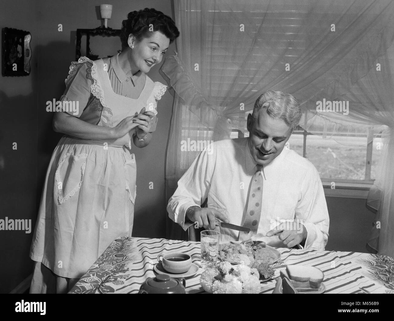 1950er Jahre MANN ESSEN ALS FRAU SCHAUT AUF - d1024DEB001 HARS OLD TIME BARBARIANS ZWEI PERSONEN SÜSSE KAUKASISCHEN SNACK GERNE FREUDE VERHEIRATET BEZIEHUNG GATTE EHEMÄNNER GROWNUP GESUNDHEIT LEBEN ZU HAUSE KOPIEREN RAUM FREUNDSCHAFT halber Länge EHE INTERESSIEREN PAARE DESSERT DRINNEN AMERICANA Nostalgie im mittleren Alter MORGEN PARTNER WINDOWS ZWEISAMKEIT Mann mittleren Alters genießen Gebäck 40-45 Jahre 45-50 JAHRE HINGABE FRAUEN GLÜCK Frau mittleren Alters trinken früh MATE SNACK FOOD froh, Stolz, FREUDE FREUDE BRUNCH GEWIDMET ENGAGEMENT SPEISEN ERFRISCHUNG B&W SCHWARZ UND WEISS KAUKASISCHEN ETHNIE FREUDE Stockfoto