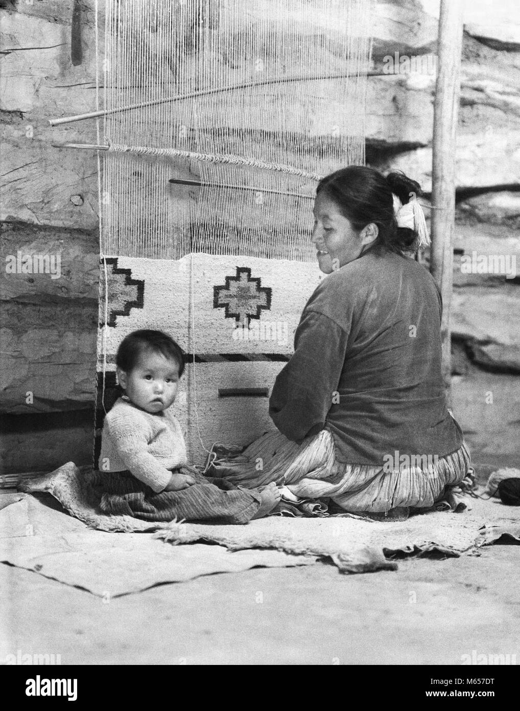 1930er lächelnd NATIVE AMERICAN NAVAJO FRAU MUTTER WEBEN TEPPICH SITZT AM WEBSTUHL MIT BABY AN IHRER SEITE MIT BLICK AUF DIE KAMERA - ich 1203 HAR 001 HARS LIFESTYLE FRAUEN LEBEN ZU HAUSE SITZEN UNITED STATES WOLLE KOPIE RAUM mit halber Länge Damen traditionellen Inder, die VEREINIGTEN STAATEN VON AMERIKA NAVAJO DRINNEN NOSTALGIE ZWEISAMKEIT AUGENKONTAKT 25-30 Jahre 30-35 JAHRE MAMMEN TRADITION, Kreativität und Kultur native american 6-12 Monate jungen Mitte nach Mitte der erwachsenen Frau gebürtige Amerikaner PRÄZISION WEBEN B&W SCHWARZ UND WEISS AUF KAMERA WEBSTUHL BERUFE ALTMODISCHE PERSONEN WEBER Stockfoto