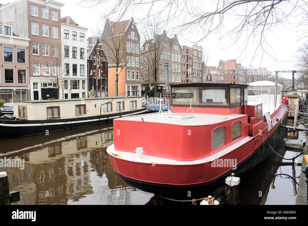 Boote Kreuzfahrt entlang schlängelnde Wasserstraßen, zu malerischen Kanal Seite Ansichten in der niederländischen Hauptstadt Amsterdam. Stockfoto