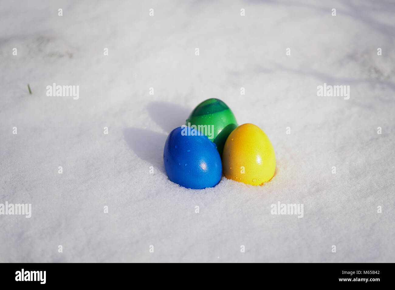 Drei Ostereier in lebendigen Farben in den frischen Schnee gemalt Stockfoto