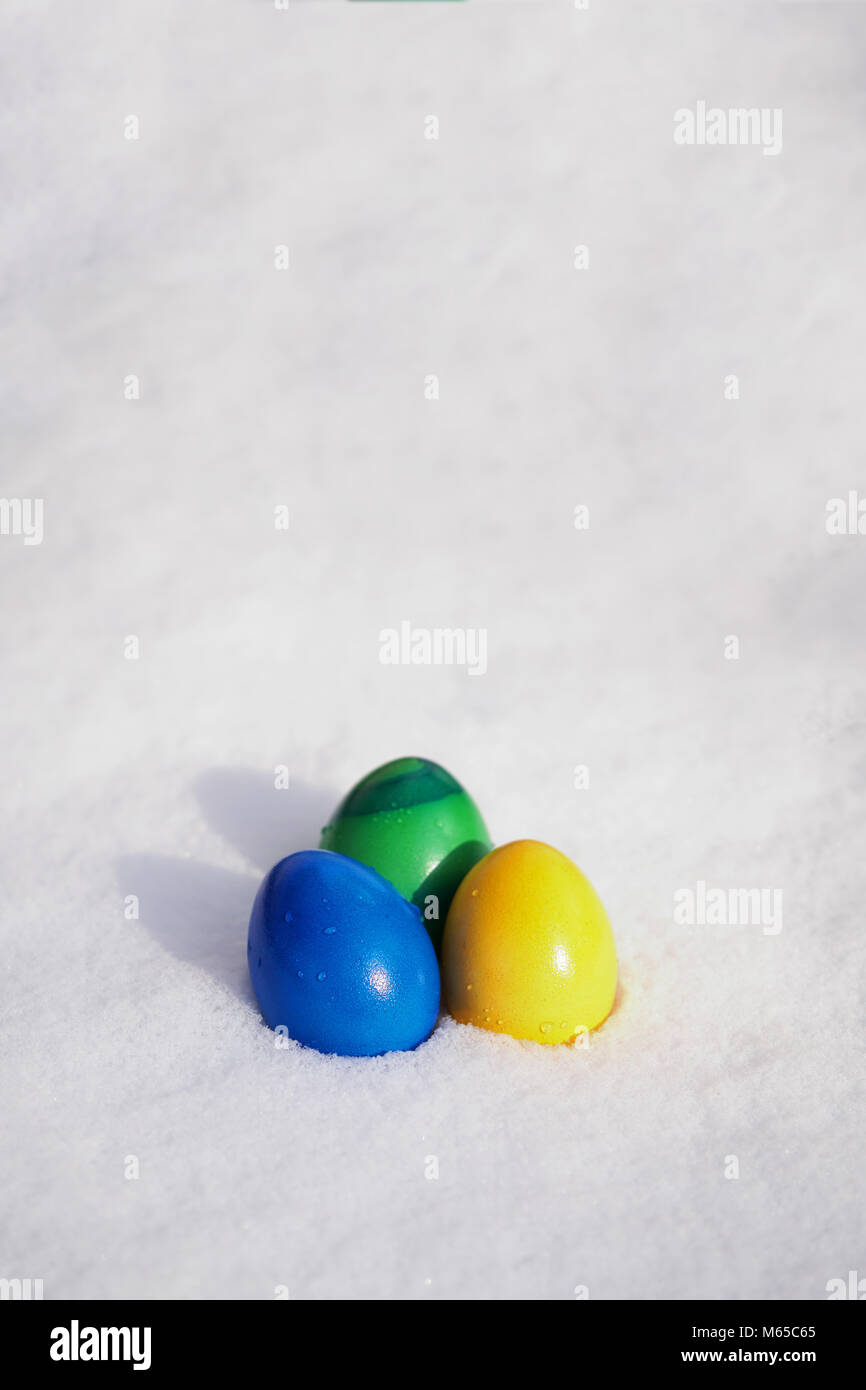 Drei Ostereier in lebendigen Farben in den frischen Schnee gemalt Stockfoto