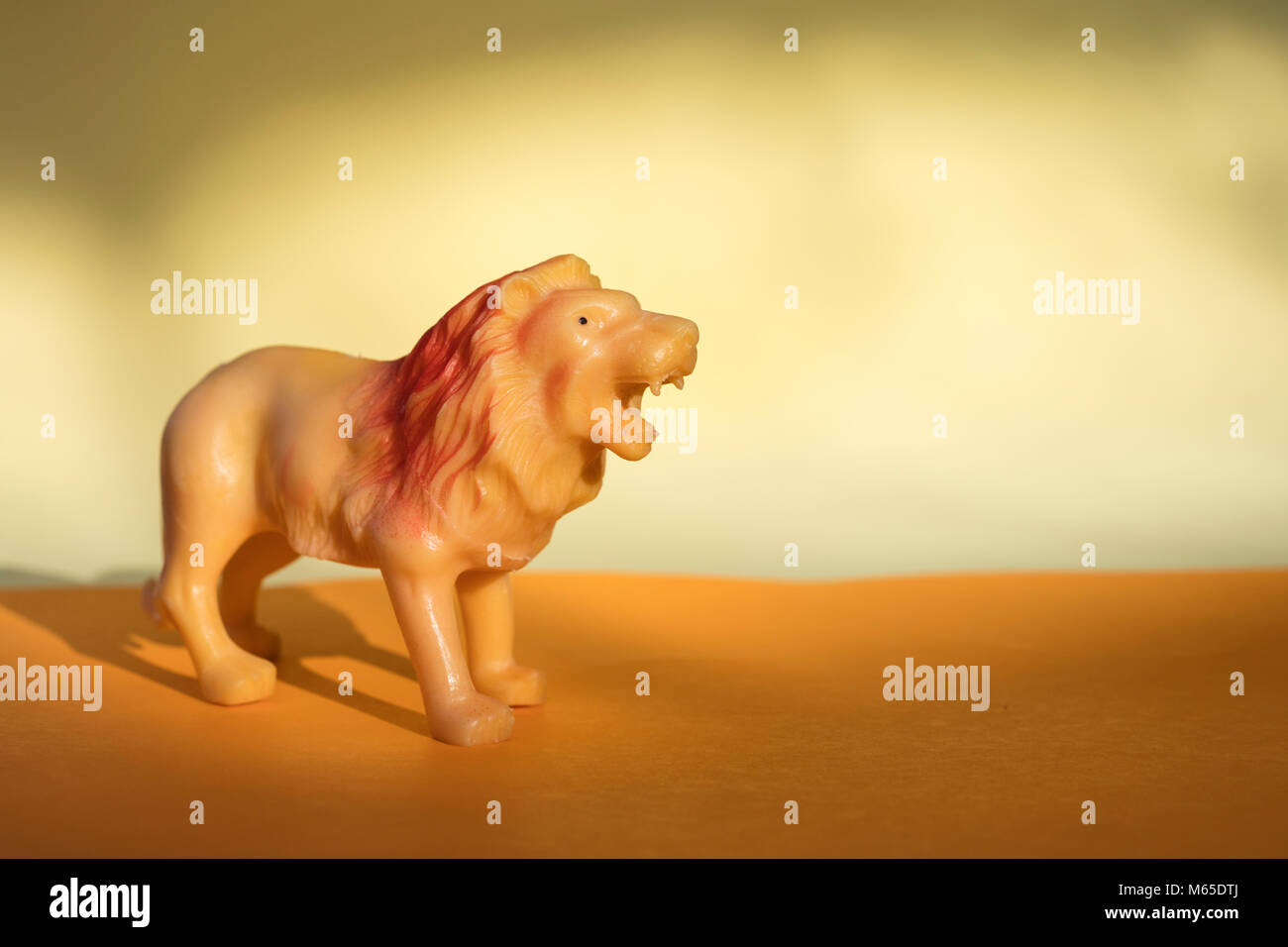 Kunststoff lion Figurine in orange hinterlegt. Stockfoto