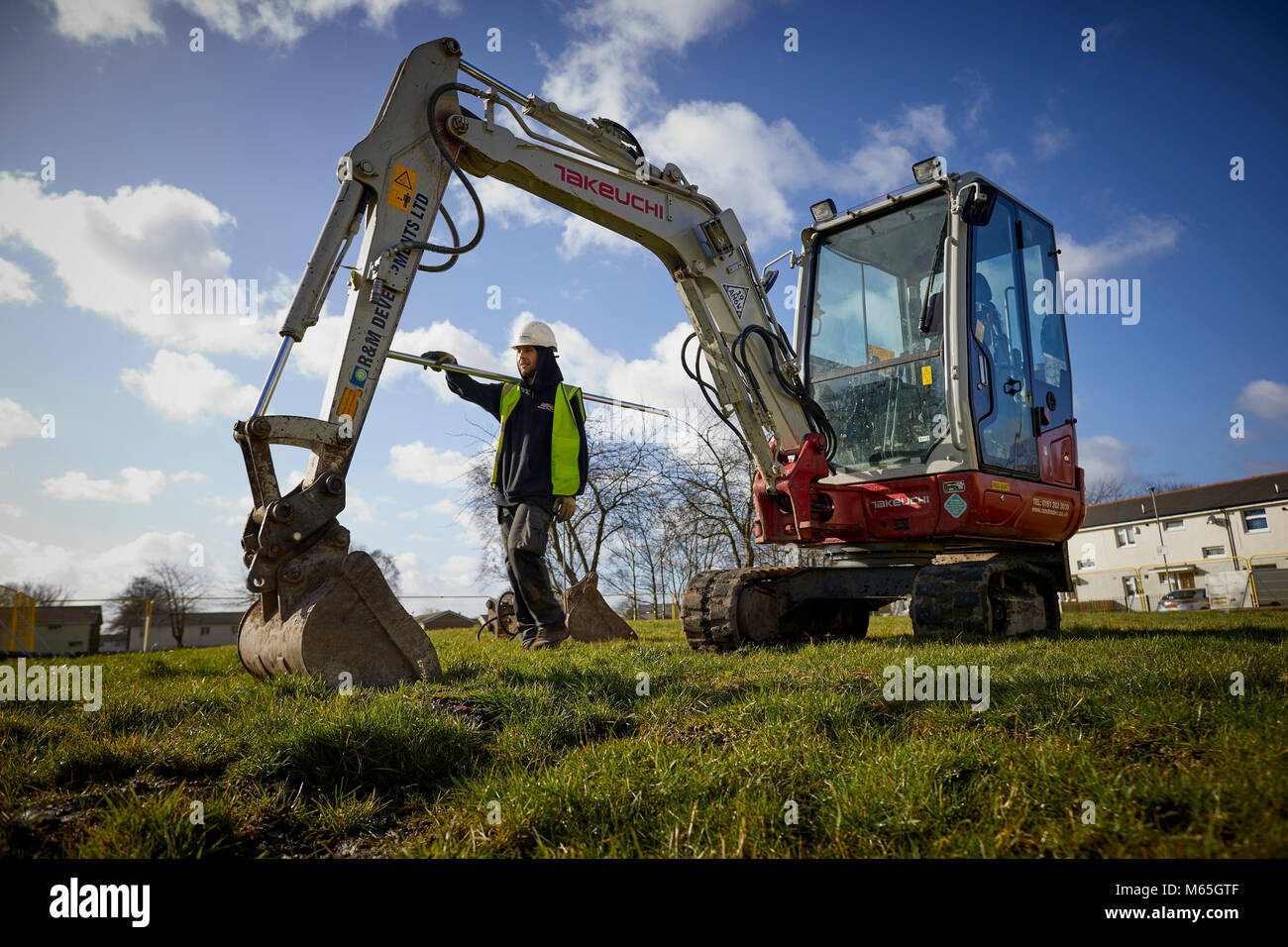 Arbeiter auf der Baustelle neben einem Mini Bagger Stockfoto