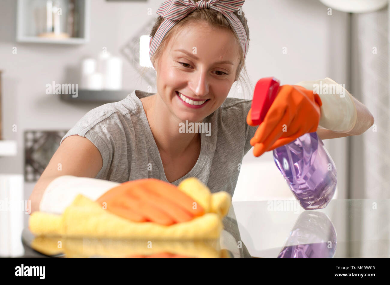 Putzfrau in gelb Handschuhe Reinigung Glas Tisch mit Spray Stockfotografie  - Alamy