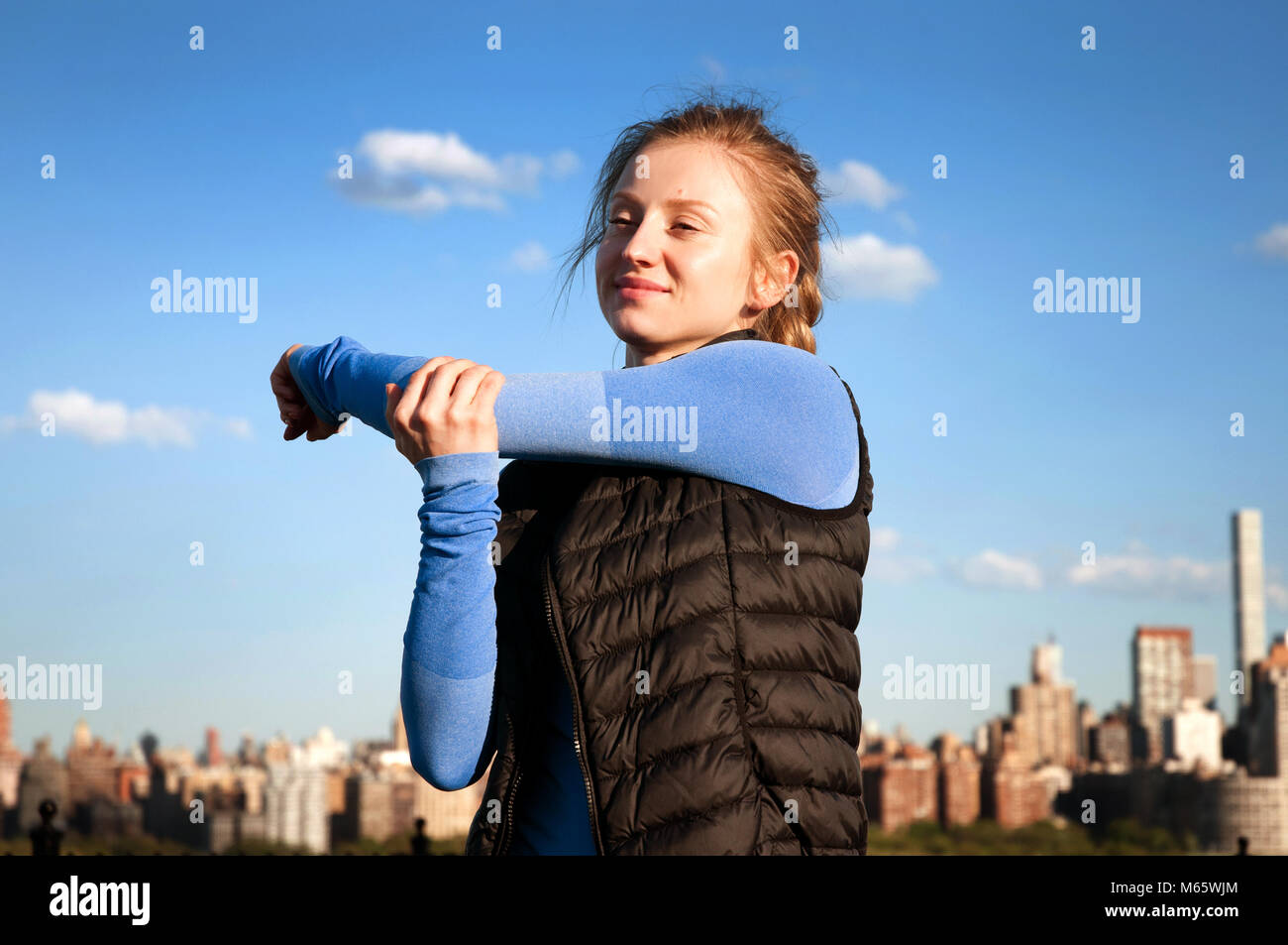 Frau tun Fitness Übung im Park mit Blick auf Downtown Manhattan New York City. Stockfoto