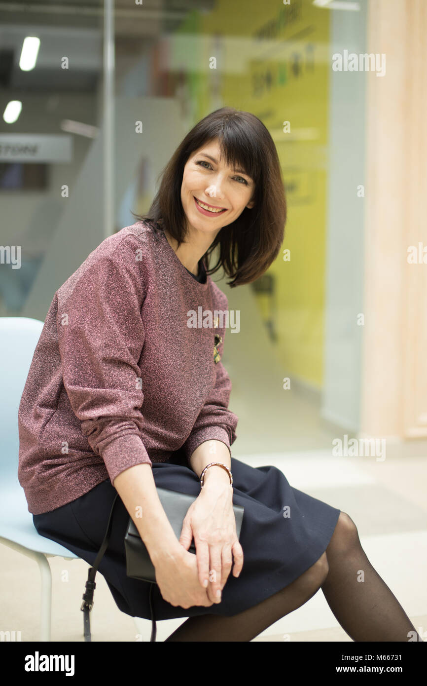 Casual Frau sitzt auf einem Stuhl und entspannen in Mall Stockfoto