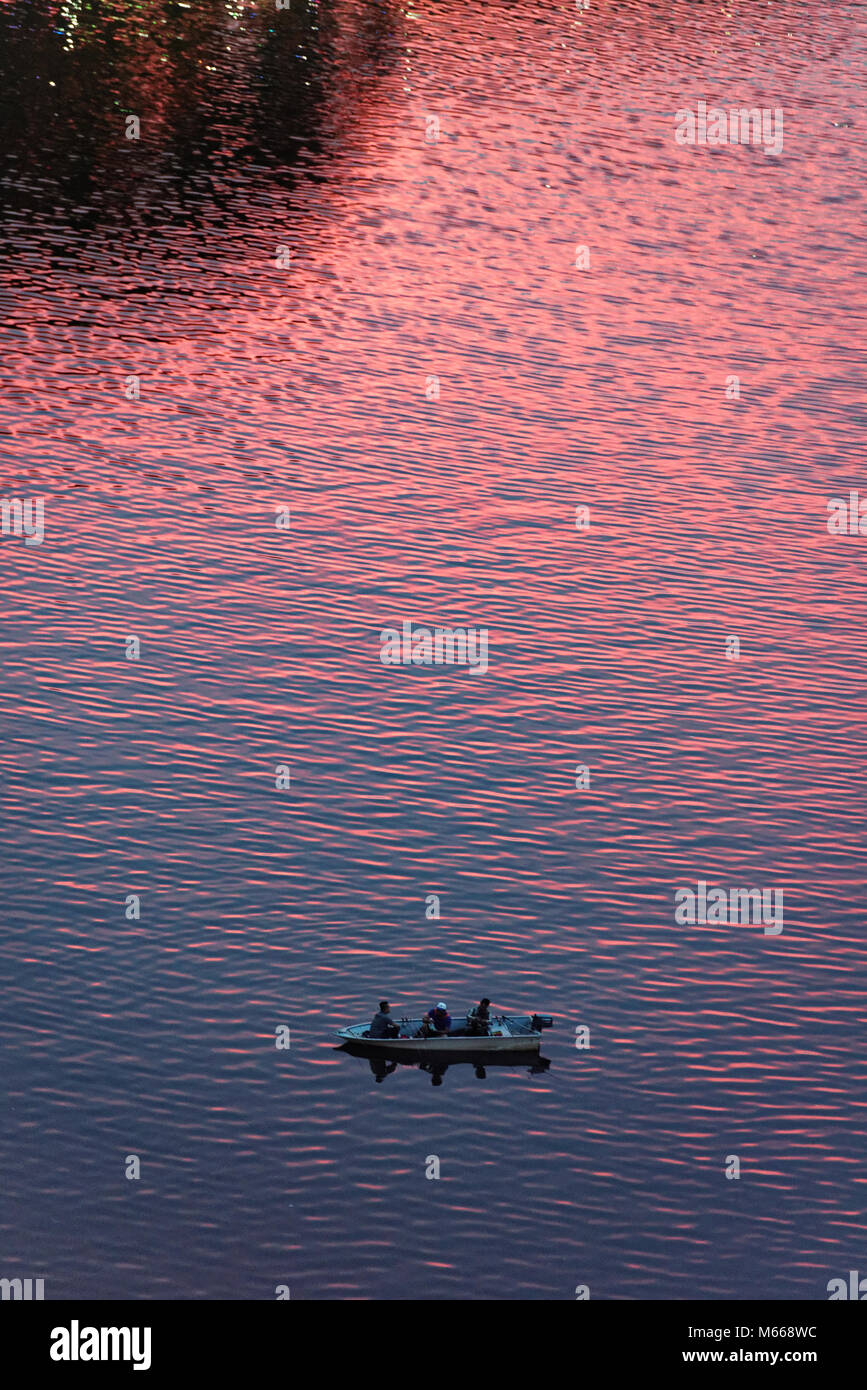 Drei Männer Fischen am Sarawak River in Kuching wie der Sonnenuntergang macht das Wasser rot Stockfoto