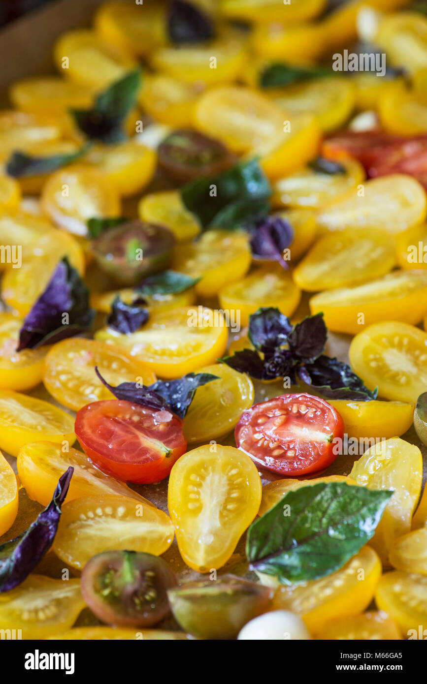 Kirsche und Traube Tomaten auf ein Backblech mit Knoblauch und Kräutern Stockfoto