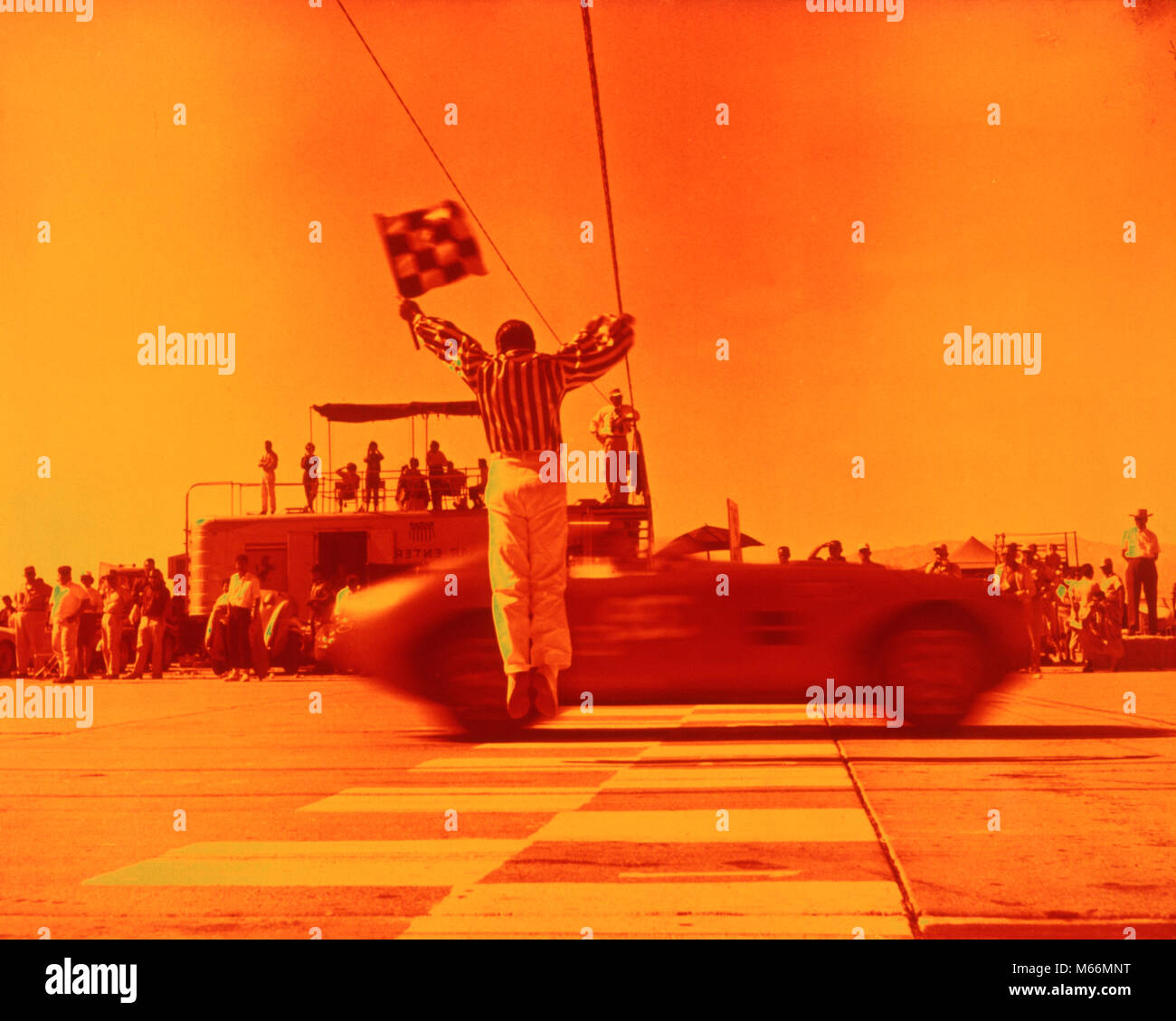 1970 s Mann winkte karierten Flagge an der Ziellinie ENDE DES SPORTS CAR RACE ORANGE FILTER - km 3108 HAR 001 HARS AUTOMOBIL UNTERHALTUNG TRANSPORT NOSTALGIE ZIELE ERFOLG ABENTEUER SIEG KRAFTFAHRZEUG AUFREGUNG FÜHRUNG FREIZEIT RICHTUNG FAHRENDE BEWEGUNGSUNSCHÄRFE MOBILITÄT SYMBOLISCHE KARIERTEN MÄNNER SPORTWAGEN ZIELLINIE ZIELLINIE BERUFE ALTMODISCHE PERSONEN Stockfoto