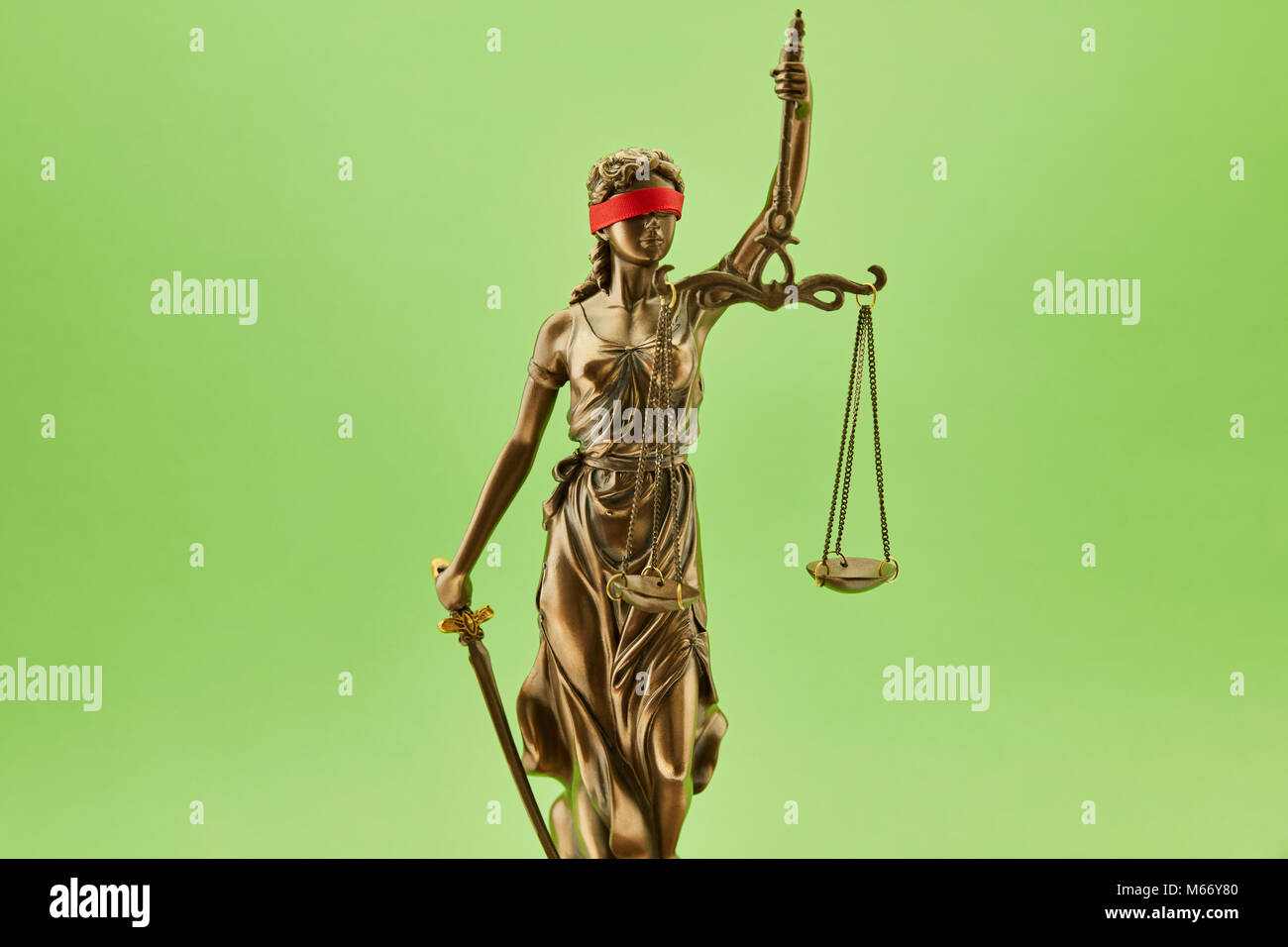 Blinde Justitia Statue als Gerechtigkeit Konzept vor einem grünen Hintergrund Stockfoto