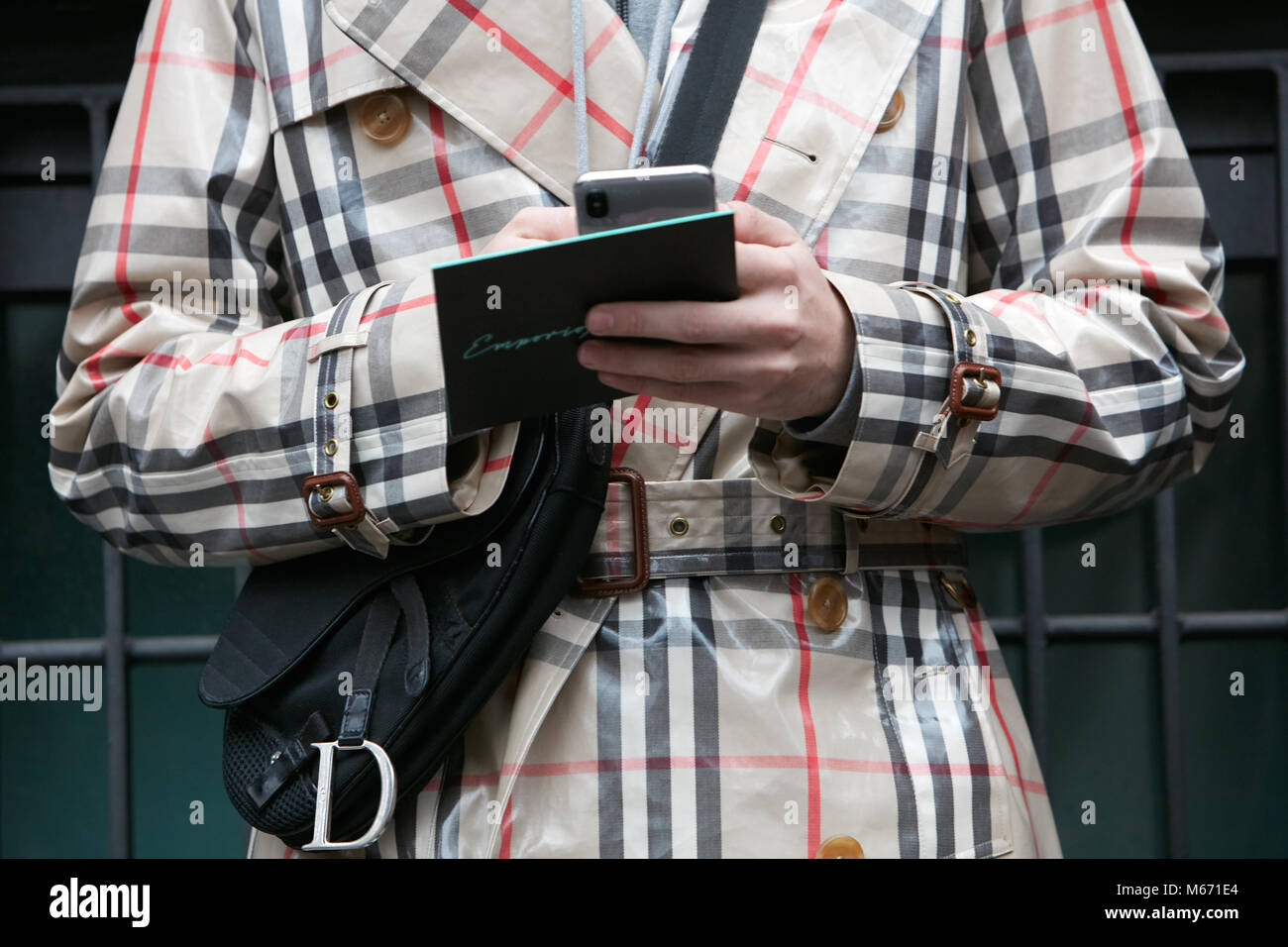 Mailand - 25. Februar: Mann mit Burberry Regenmantel und schwarzen Dior  Tasche an Smartphone suchen vor dem Emporio Armani Fashion Show, Mailand  Fashion Week Straße Stockfotografie - Alamy