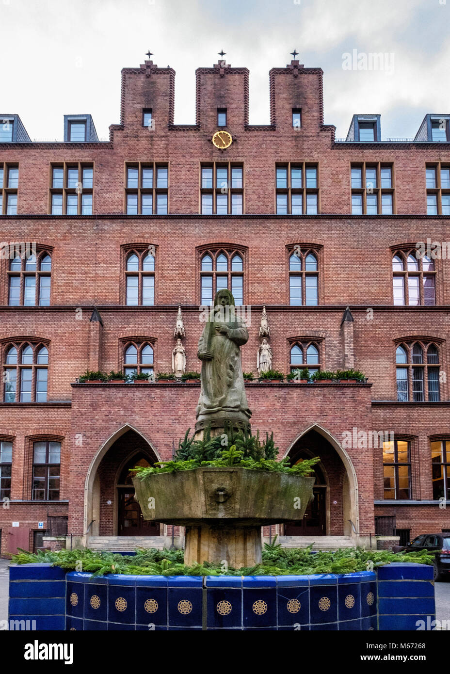 Berlin, Mitte, St. Hedwigs Krankenhaus, Haupthaus, neugotische Gebäude aus rotem Backstein außen & Fassade mit Skulpturen & Hl. Agatha Brunnen der Cl Stockfoto