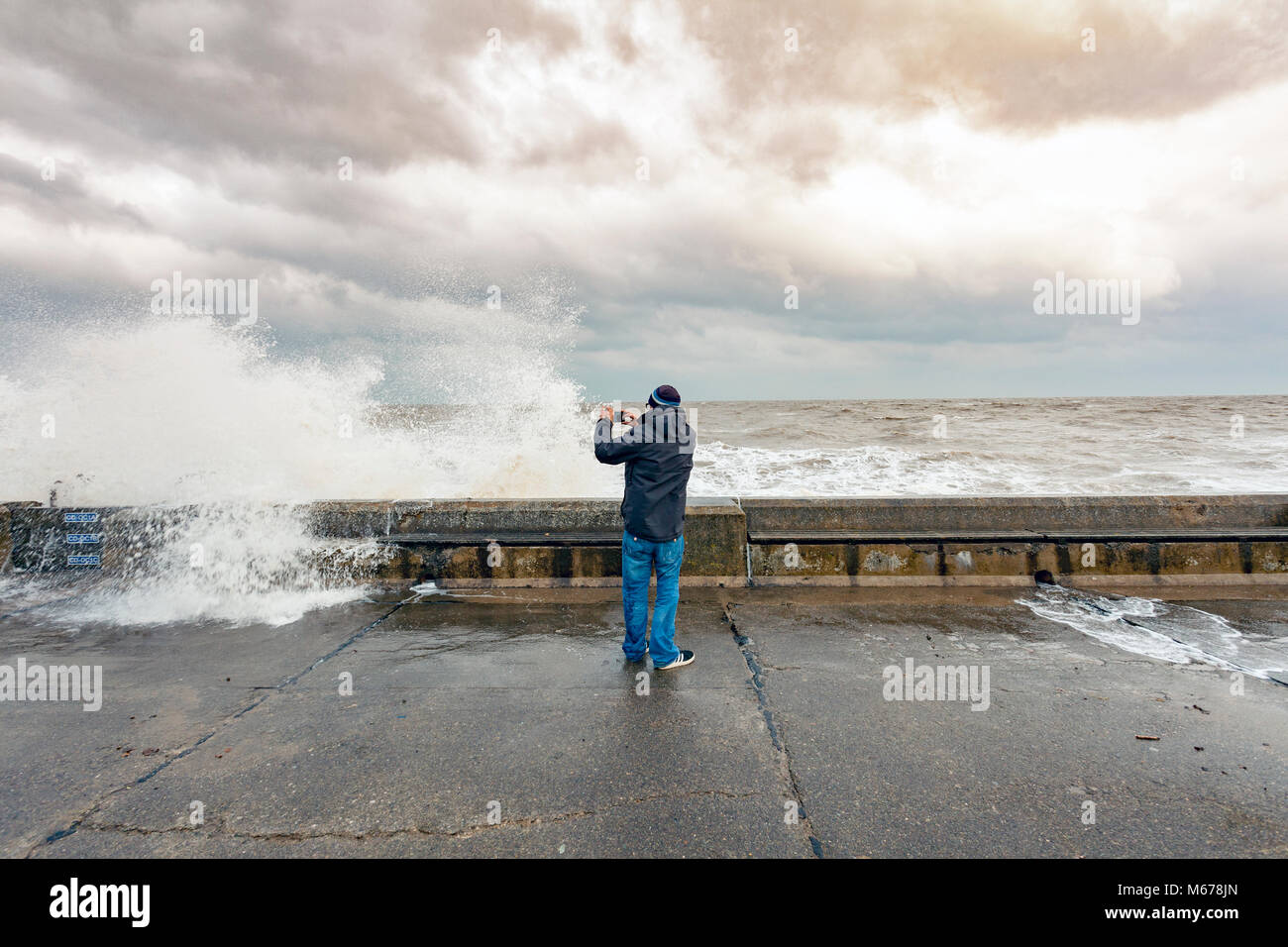 Ein Mann die Bilder der Brandung an der Promenade Wand in Colwyn Bay, Wales als Ergebnis des Tieres aus dem Osten und Sturm Emma riesige zerstörerische Wellen entlang der Küste Stockfoto