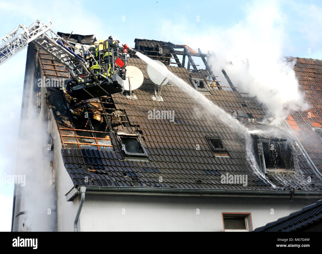 01 März 2018, Deutschland, Gelsenkirchen: Feuerwehrmänner im Dachgeschoss Feuer in einem Mehrfamilienhaus löschen. Mehrere Menschen wurden verletzt, eine Person wird noch vermisst. Foto: Roland Weihrauch/dpa Stockfoto