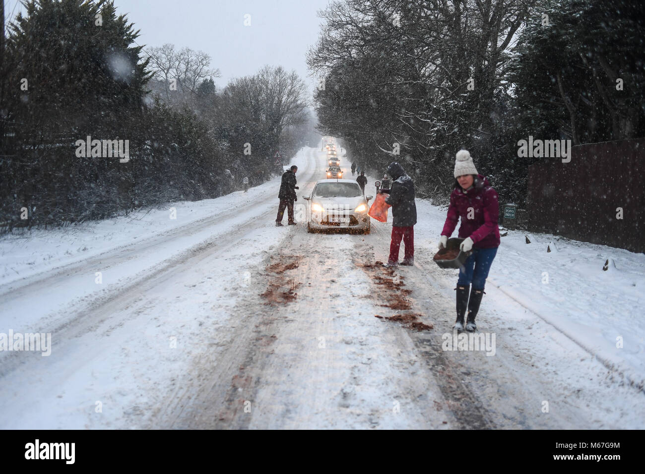Southampton, Großbritannien. 1. März, 2018. Donnerstag, 1. März 2018 UKsnow West Wellow Southampton, England. Gemeinschaft spirt, ein paar Freunde, die in der Nähe der A36 live Gießen grit auf der Straße und hilft gestrandeten push Autofahrer auf einem der vielen Hügel entlang der Route in Richtung Southampton Rubrik von Salisbury. Sturm Emma kombiniert mit dem "Tier aus dem Osten' hits West Wellow, Romsey Hampshire am späten Nachmittag verursacht Chaos auf der A36 die Hauptroute von Southampton nach Salisbury. Autos und Lastwagen auf die vielen Hügel blockiert Verkehr stecken geblieben. Credit: PBWPIX/Alamy leben Nachrichten Stockfoto