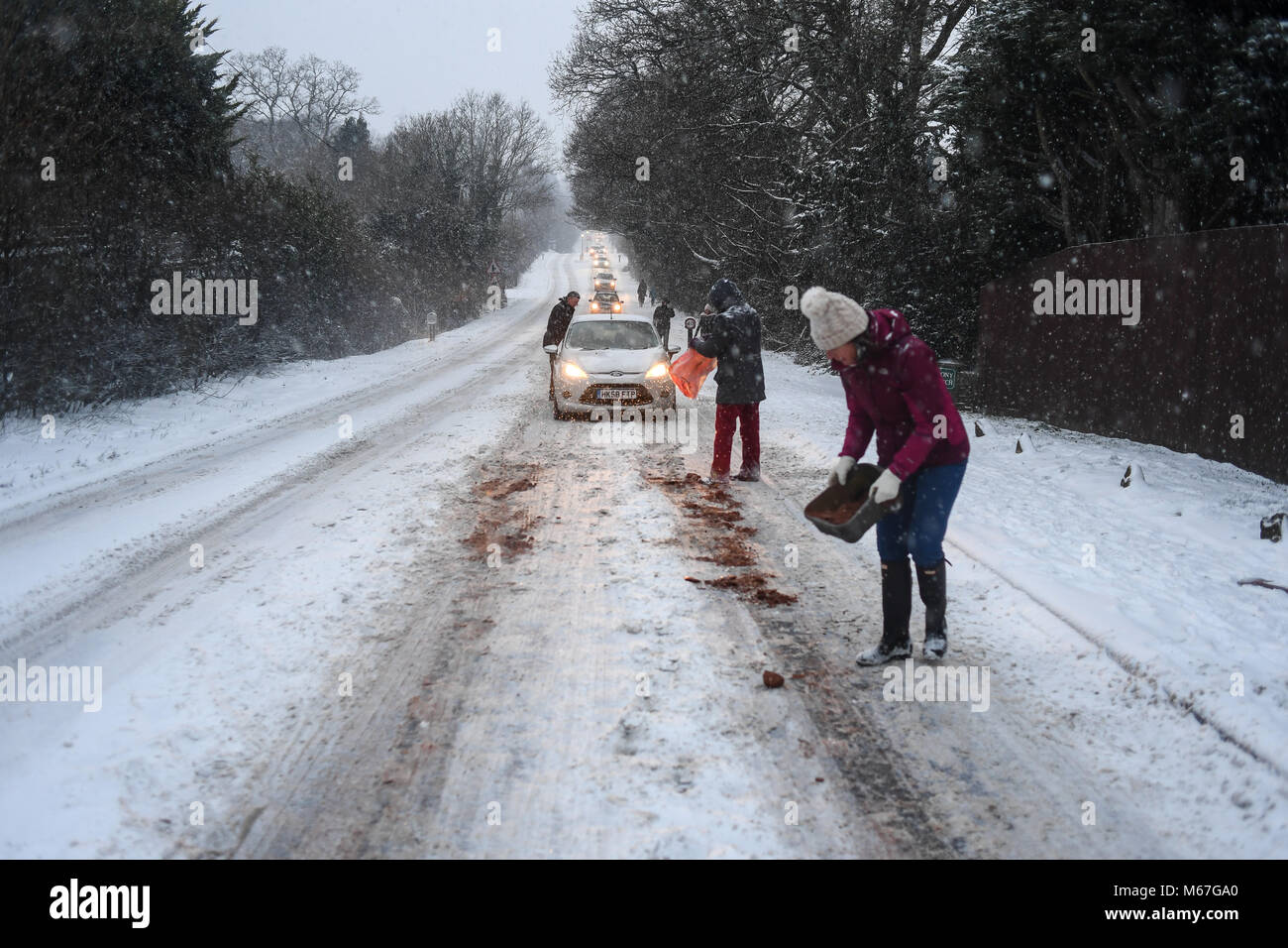 Southampton, Großbritannien. 1. März, 2018. Donnerstag, 1. März 2018 UKsnow West Wellow Southampton, England. Gemeinschaft spirt, ein paar Freunde, die in der Nähe der A36 live Gießen grit auf der Straße und hilft gestrandeten push Autofahrer auf einem der vielen Hügel entlang der Route in Richtung Southampton Rubrik von Salisbury. Sturm Emma kombiniert mit dem "Tier aus dem Osten' hits West Wellow, Romsey Hampshire am späten Nachmittag verursacht Chaos auf der A36 die Hauptroute von Southampton nach Salisbury. Autos und Lastwagen auf die vielen Hügel blockiert Verkehr stecken geblieben. Credit: PBWPIX/Alamy leben Nachrichten Stockfoto