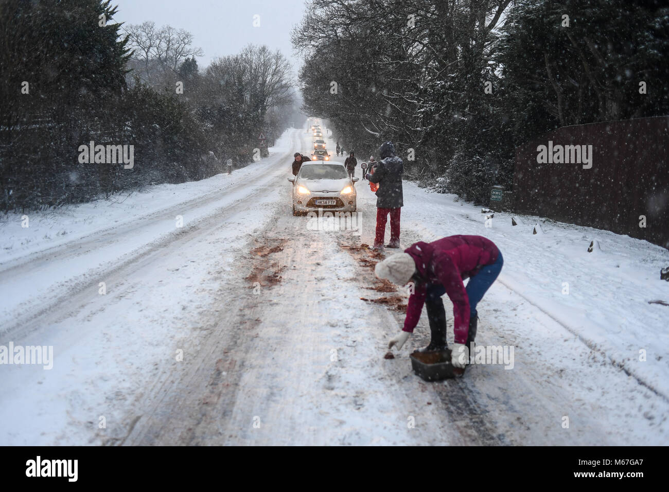 Southampton, Großbritannien. 1. März, 2018. Donnerstag, 1. März 2018 UKsnow West Wellow Southampton, England. Gemeinschaft spirt, ein paar Freunde, die in der Nähe der A36 live Gießen grit auf der Straße und hilft gestrandeten push Autofahrer auf einem der vielen Hügel entlang der Route in Richtung Southampton Rubrik von Salisbury. Sturm Emma kombiniert mit dem "Tier aus dem Osten' hits West Wellow, Romsey Hampshire am späten Nachmittag verursacht Chaos auf der A36 die Hauptroute von Southampton nach Salisbury. Autos und Lastwagen auf die vielen Hügel blockiert Verkehr stecken geblieben. Credit: PBWPIX/Alamy leben Nachrichten Stockfoto
