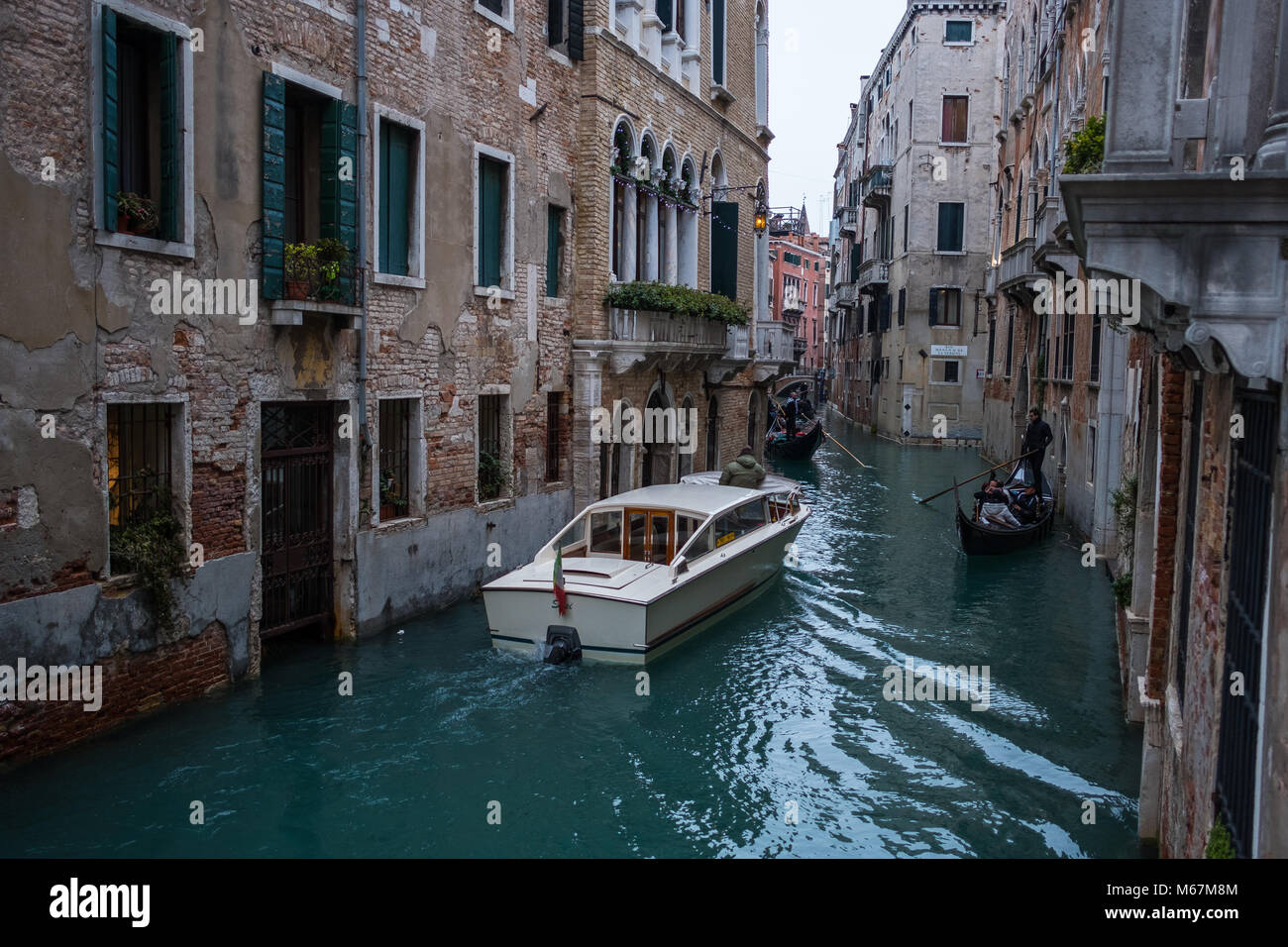 Wasserkanäle in Venedig mit bewegtem Boot, keine Menschenmenge und keine identifizierbare Person im Winter und klarem weißen Himmel. Stockfoto