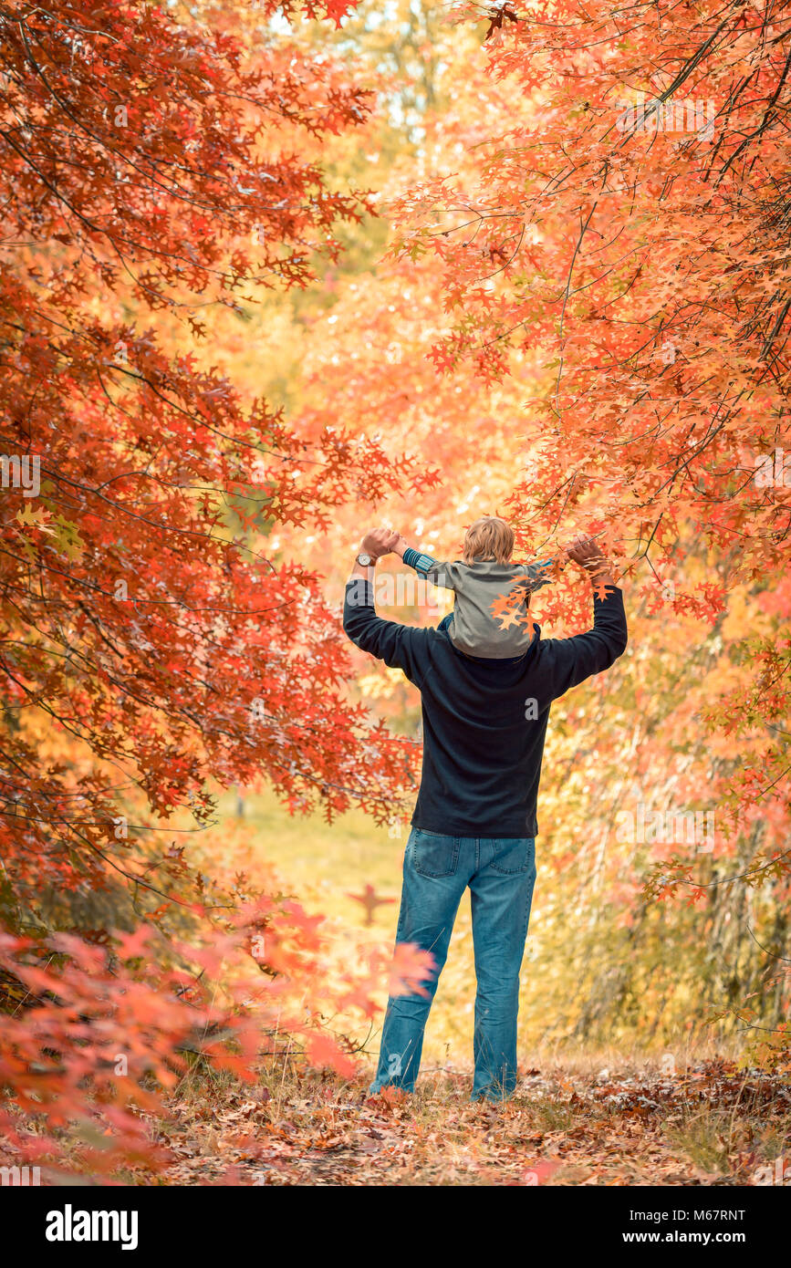 Vater Sohn piggyback Ride im Herbst Park Stockfoto