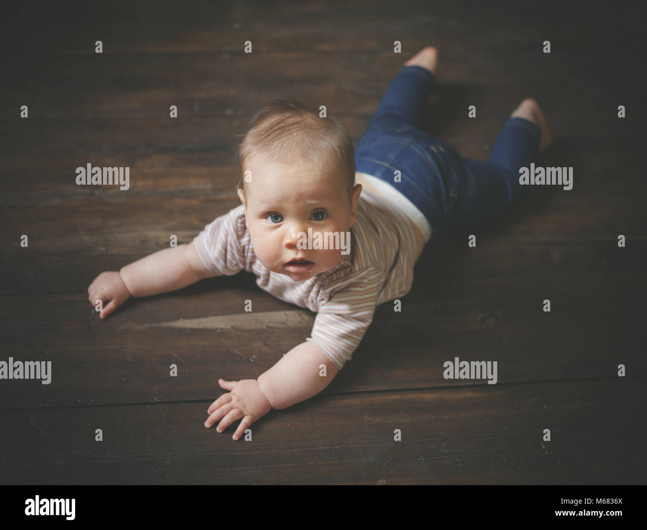Ein kleines Baby liegt auf einem Holzboden Stockfoto