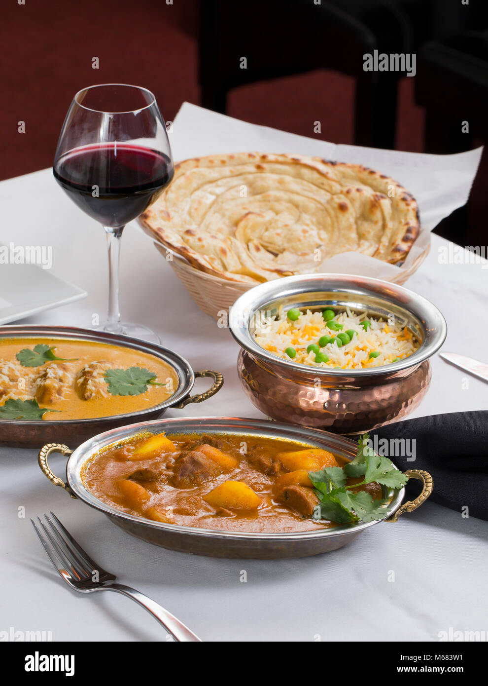 Indische Curry essen verteilen sich auf ein phantastisches Abendessen Tabelle mit Reis, laccha Paratha, Lamm aam Wala, Safran Malai Kofta, Rotwein. Stockfoto