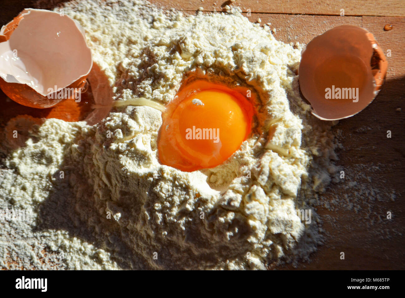 Schließen Sie bis zu Eigelb in weißes Mehl mit gebrochenen Eierschalen auf Holz board Stockfoto