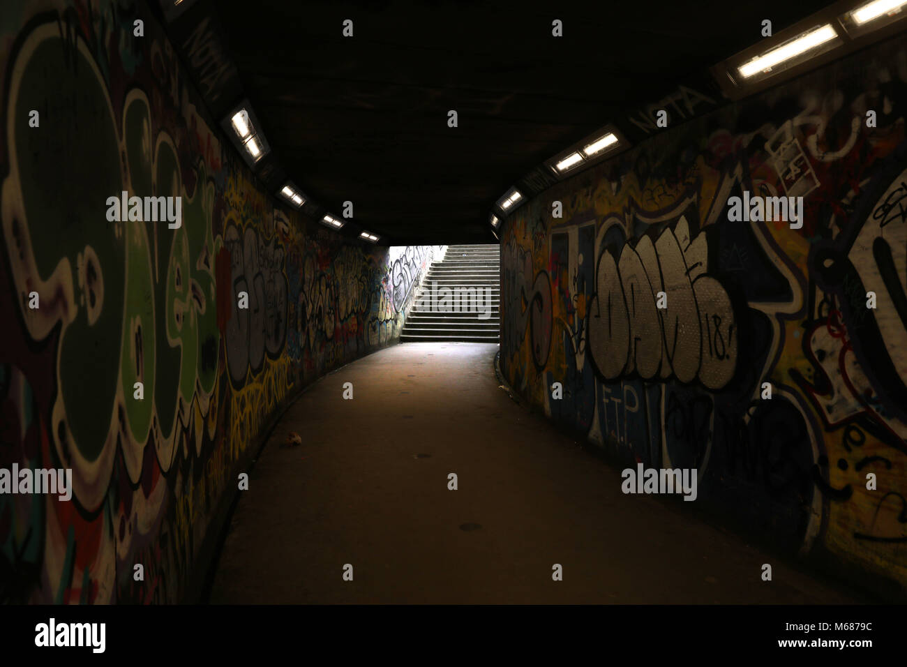 Licht am Ende des Tunnels, dunkle U-Bahn Tunnel mit Graffiti und Schritte Stockfoto