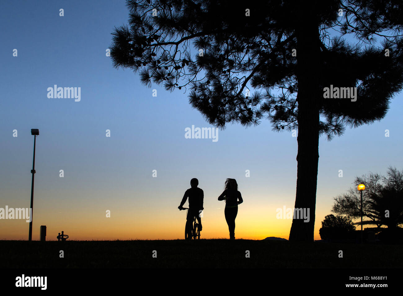 In Argeles-sur-Mer (Frankreich). Zwei junge Leute, ein Mountainbike und läuft entlang der Uferpromenade am frühen Morgen Stockfoto