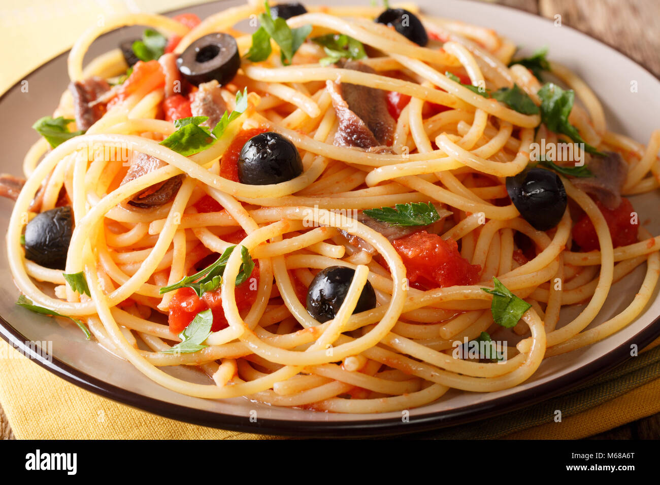 Pasta alla Puttanesca mit Sardellen und schwarzen Oliven Makro auf einem Teller. Horizontale Stockfoto