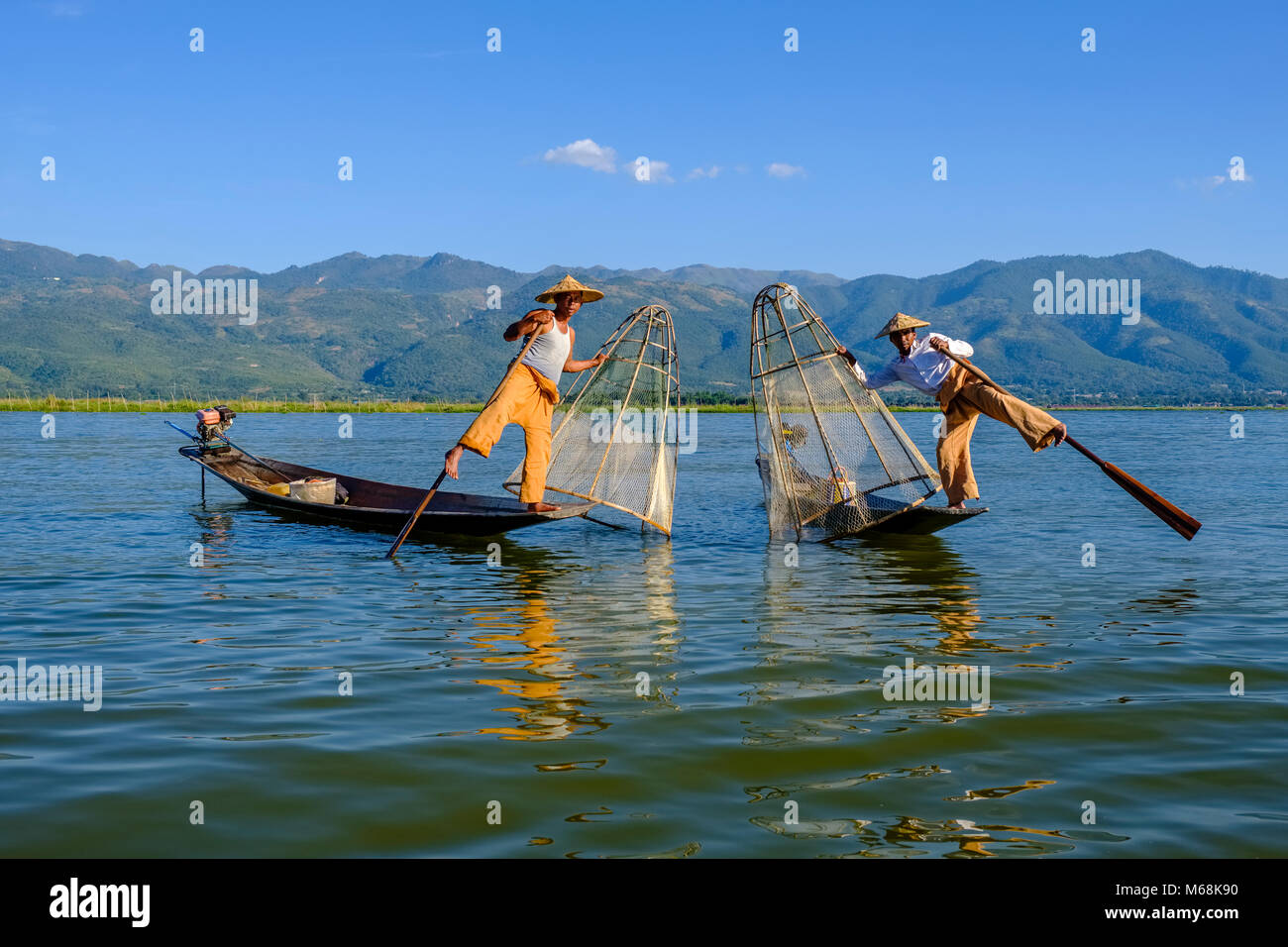 Fischer, stehend auf ihren Booten, posierend, fischen die traditionelle Art und Weise auf dem Inle See Stockfoto