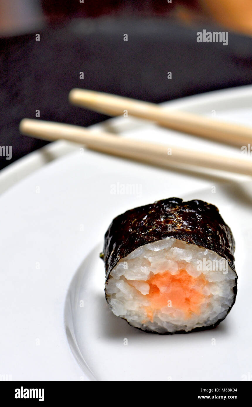 Sushi auf einem weißen Teller: Maki (Rolle in Algen umwickelt) und Stäbchen Stockfoto