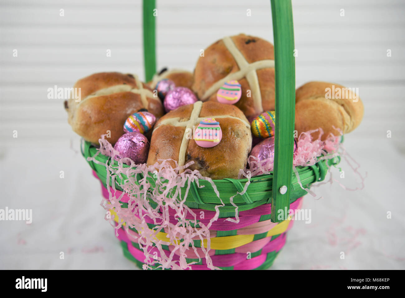 Kulinarische Ostern in einem Korb mit Hot Cross Buns und Schokolade Ostereier ein ideales Geschenk Stockfoto