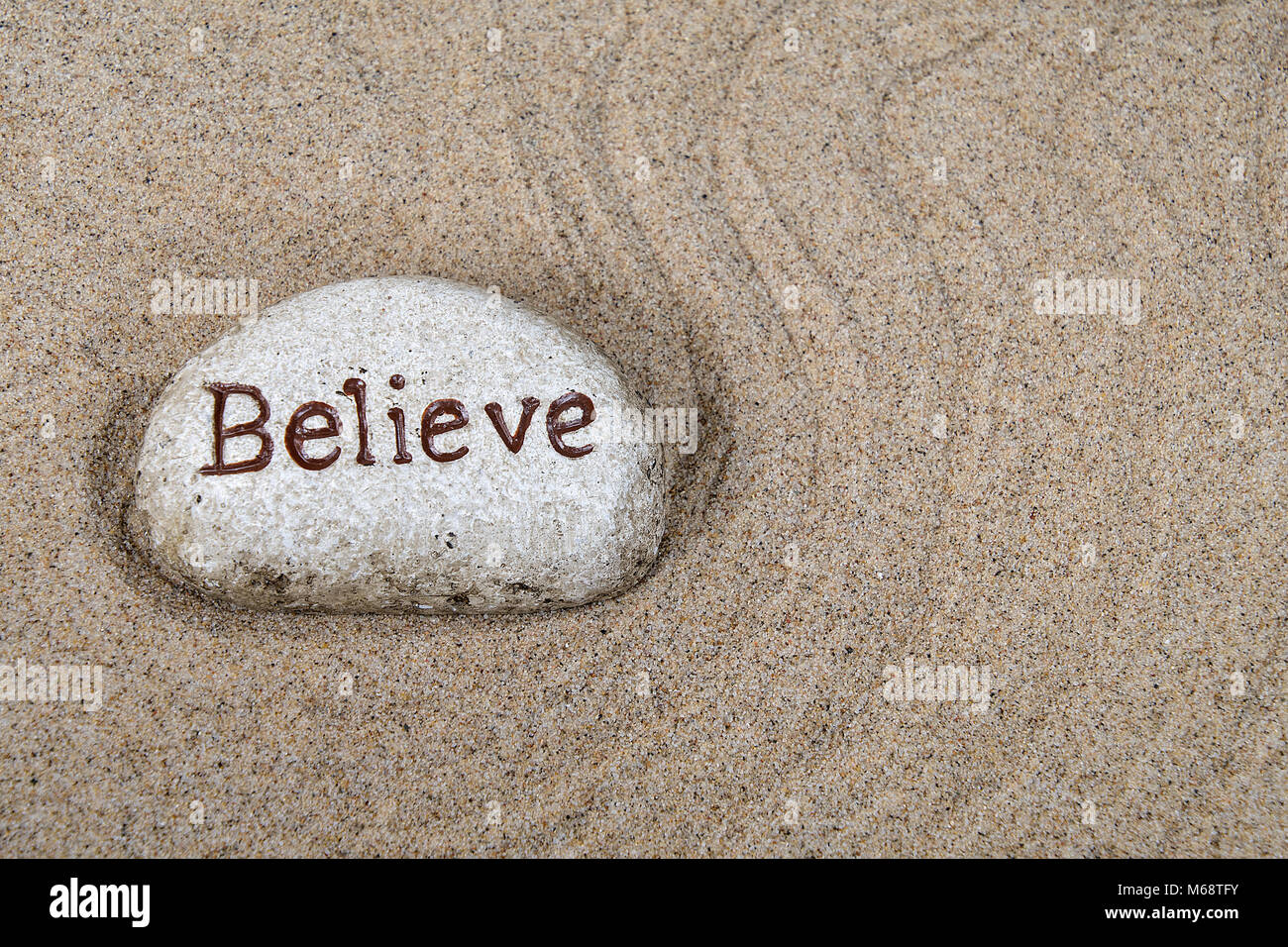 Nahaufnahme der Stein mit Glauben Text in Geharkten Strand sand Pattern Stockfoto
