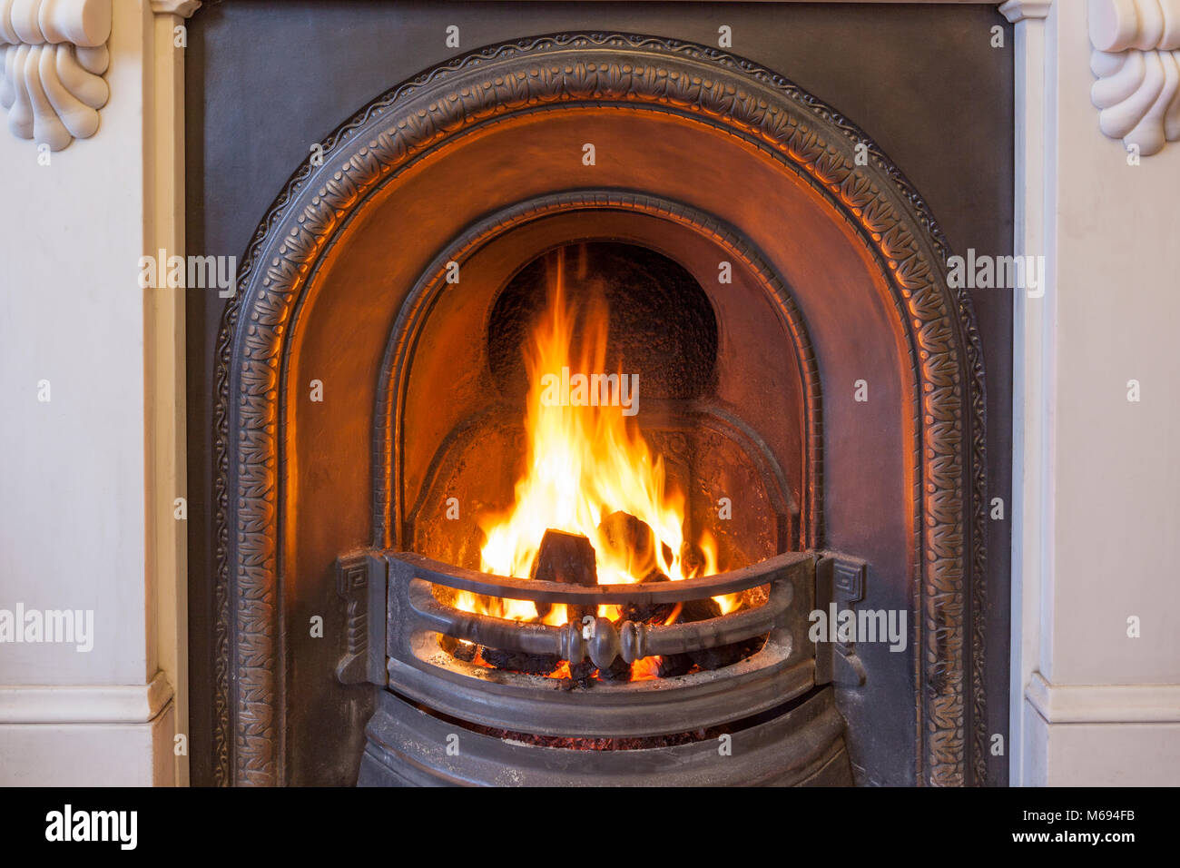 Ein brüllender Kohle Feuer in einer gusseisernen Gitter in einen Kamin aus Marmor. Stockfoto