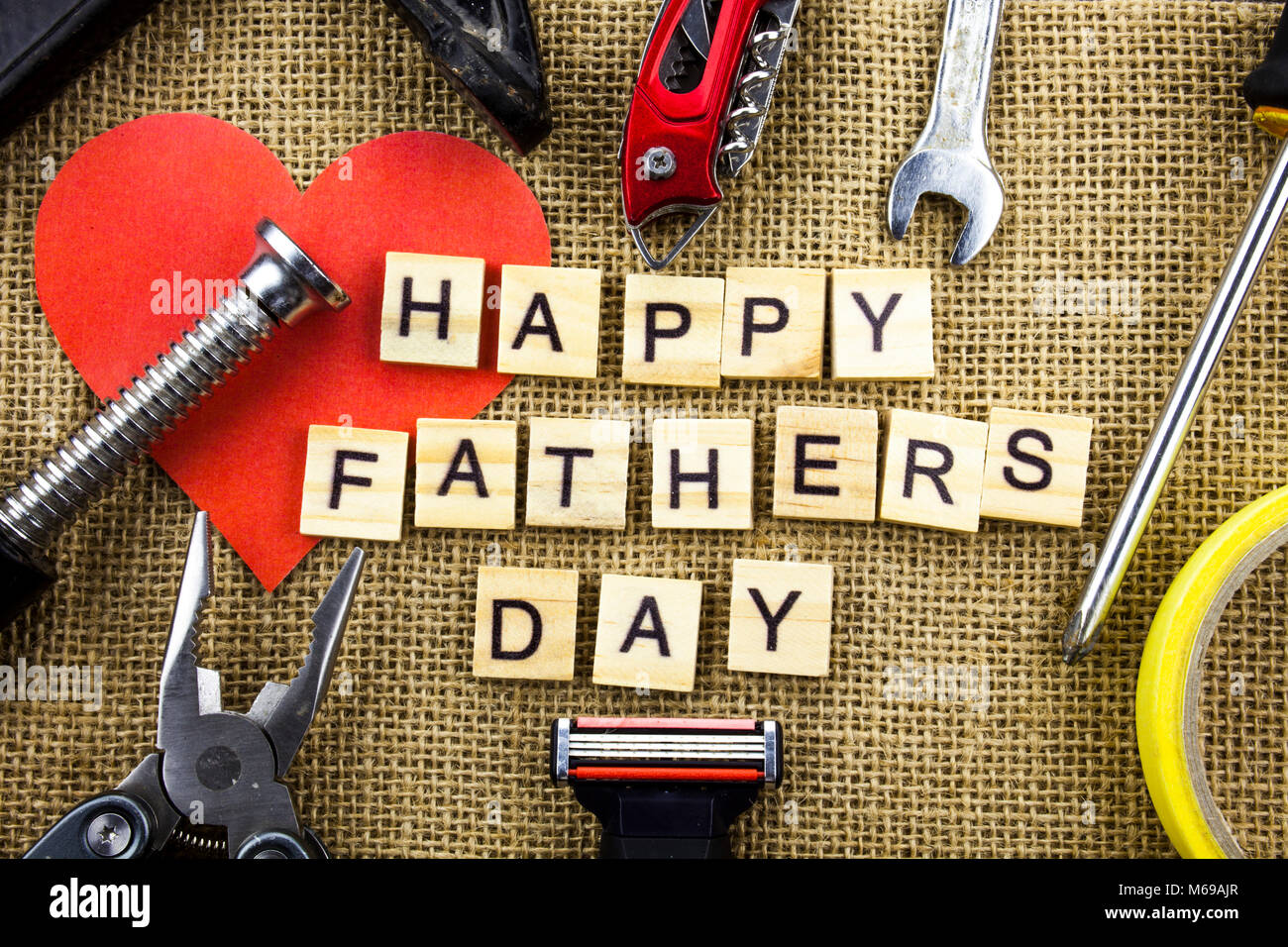 Happy Vatertag Nachricht auf einem hessischen Jute Hintergrund mit Rahmen von Werkzeugen und Bindeband. Stockfoto