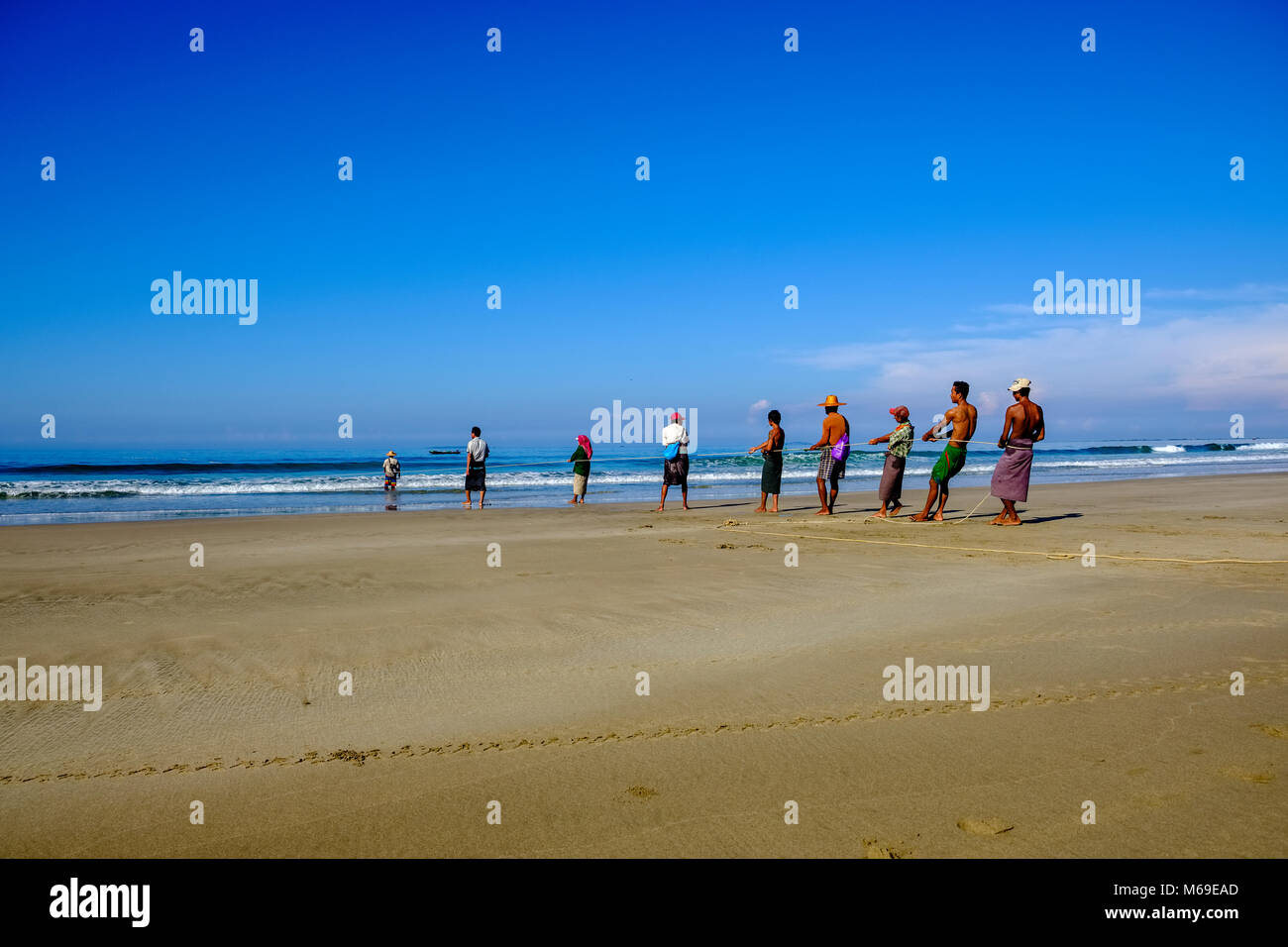 Eine Gruppe von Fischern zieht ein Fischernetz aus dem Meer am Strand Stockfoto