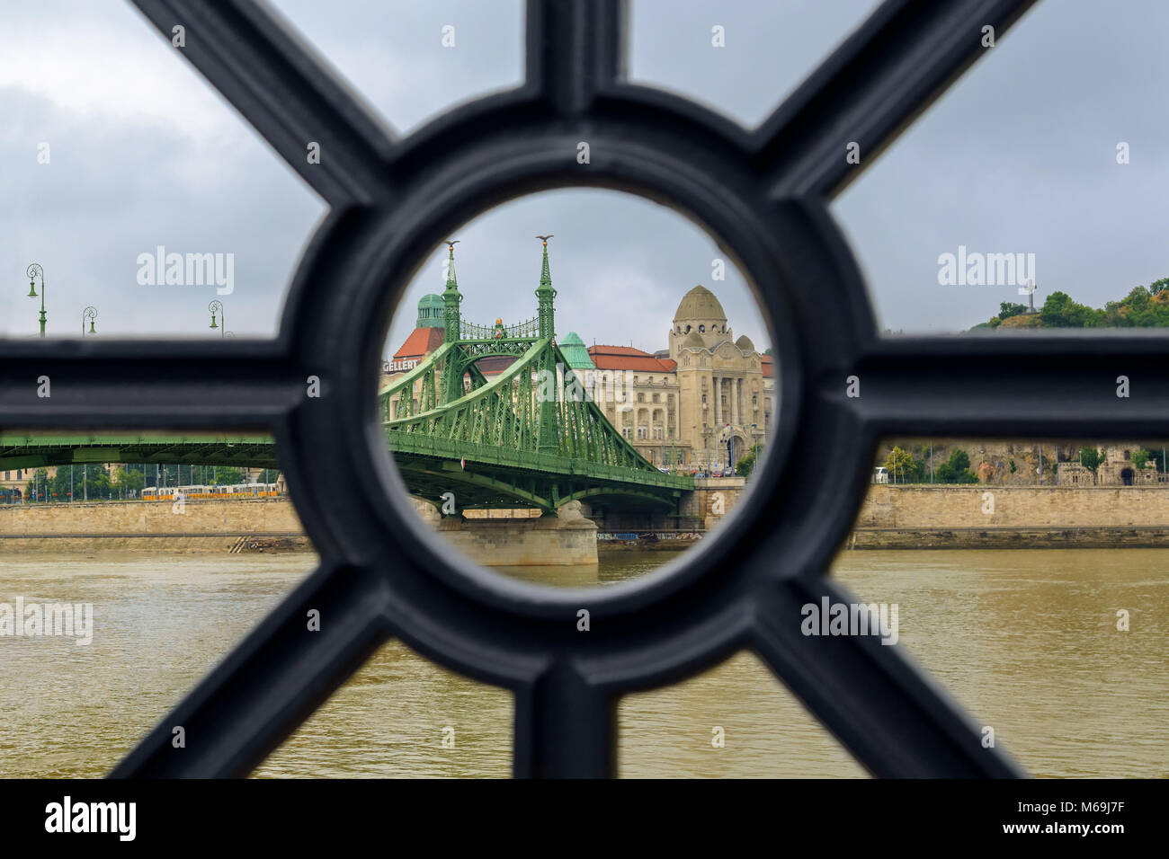 Liberty Bridge und Gellert Bad Ansicht throurh das Loch in das Donau Eisen Zaun aus Gusseisen Stockfoto