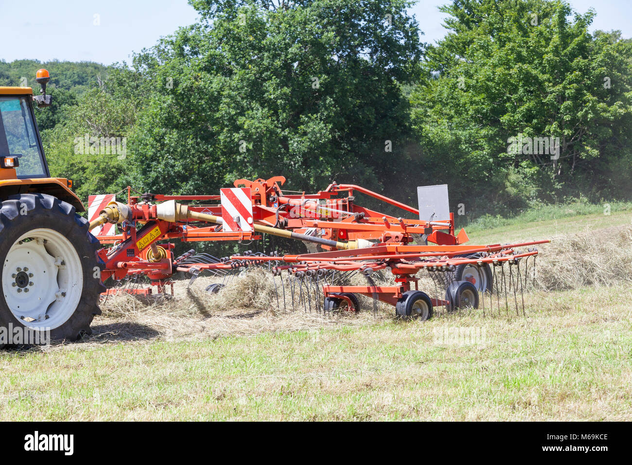 Nahaufnahme Detail eines landwirtschaftlichen rotierenden Rechen harken frisch geschnittene getrocknete Gras für Heu in eine landwirtschaftliche Weide hinter einem Traktor gezogen wird. Einige Stockfoto