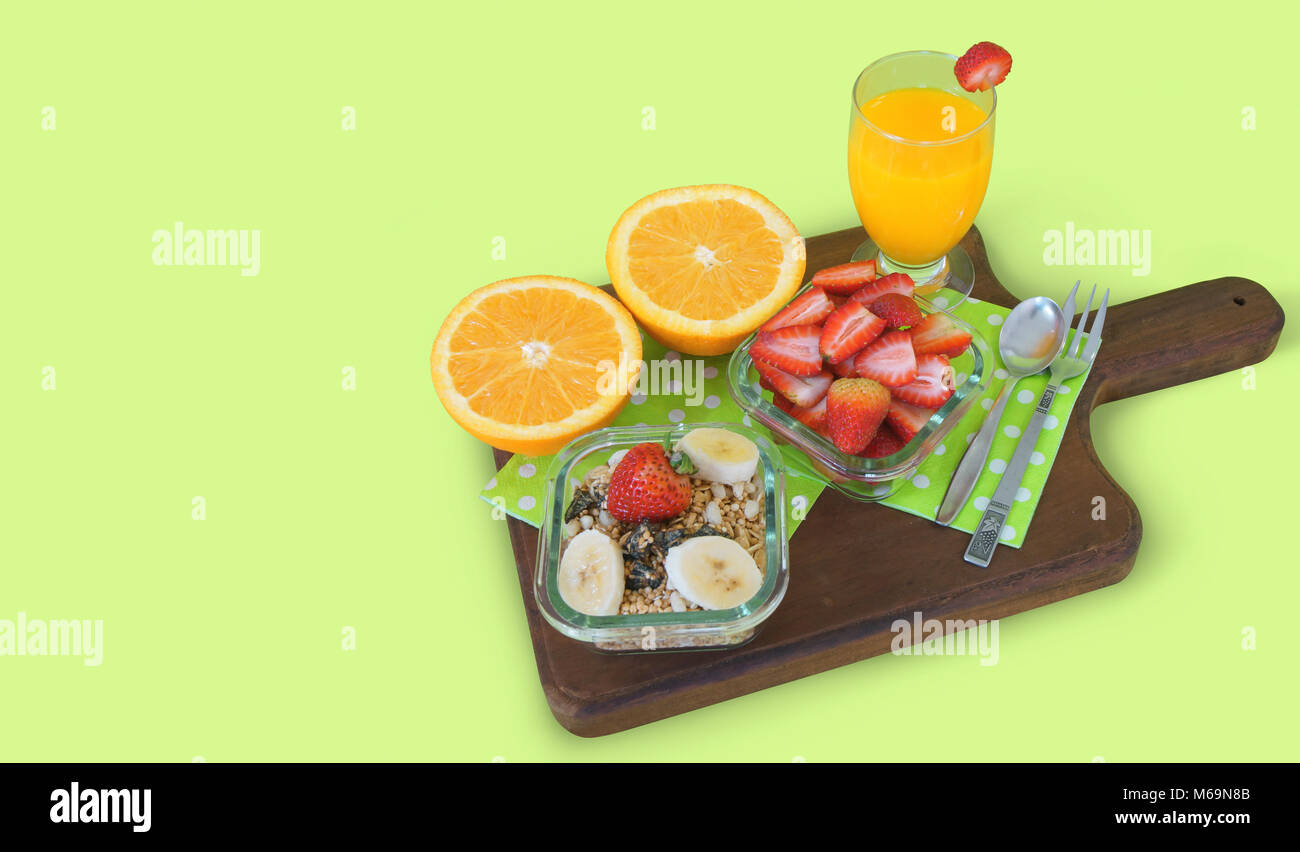 Gesundes Frühstück. Glas Topf mit gehackt Erdbeeren, Glas Topf mit Müsli mit Banane mit Glas Schale mit Orangensaft serviert. Stockfoto