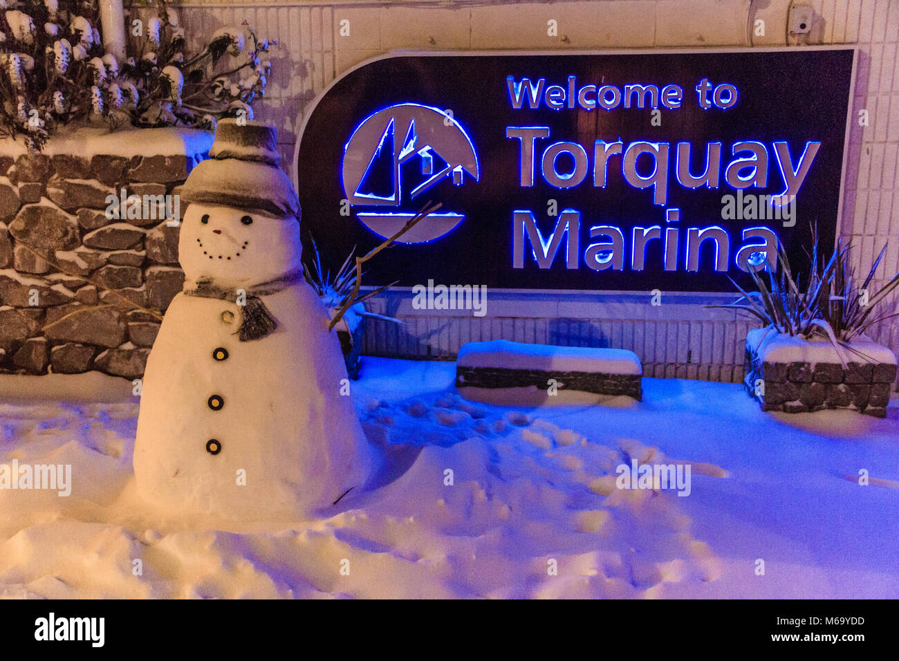 Ein Schneemann neben ein Zeichen freundliche Menschen nach Torquay Marina. Schnee fiel im März 2018 während des Sturms als "das Tier bekannt aus dem Osten'. Torquay, Devon, Großbritannien. 1. März 2018. Stockfoto