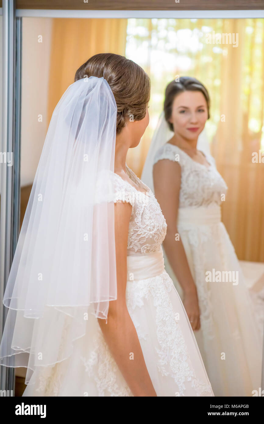 Schöne junge Braut im Brautkleid im Spiegel zu betrachten Stockfoto
