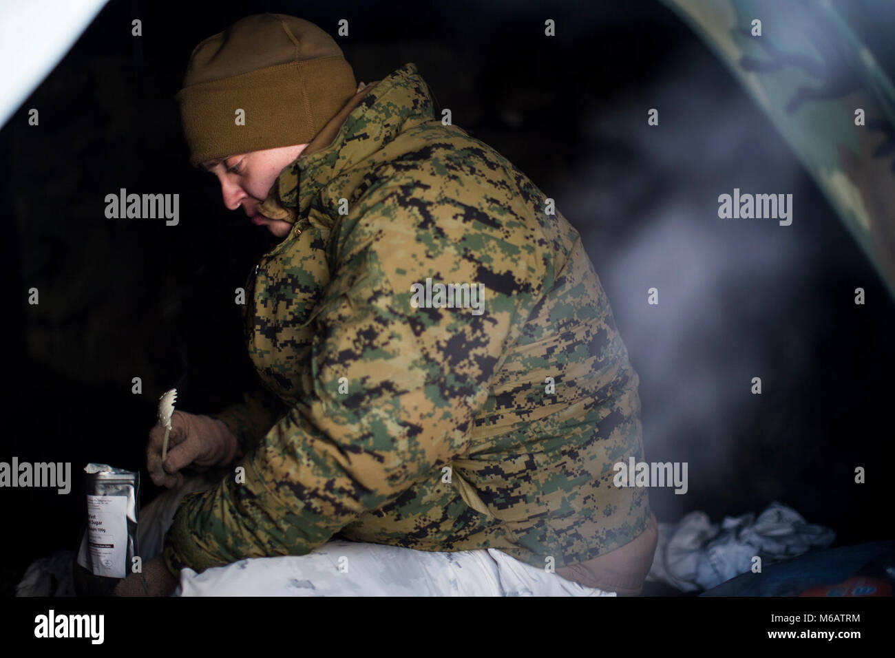 Marine mit Marine Rotational Force-Europe versucht, eine Mahlzeit - Ready-to-eat Essen, während im Bereich Ausbildung übung Teil der Übung weiß Claymore in der Nähe von Bardufoss, Norwegen, 14. Februar 2018 versucht, um warm zu bleiben. Weiß Claymore ist einer in Großbritannien Royal Marines - LED-Training in Nordnorwegen, auf Winter Kriegsführung, einschließlich Schulung auf Bewegung im negativen Terrain und über Schnee konzentriert, und die Ausbildung in defensive und offensive Operationen bei winterlichen Bedingungen. (U.S. Marine Corps Stockfoto