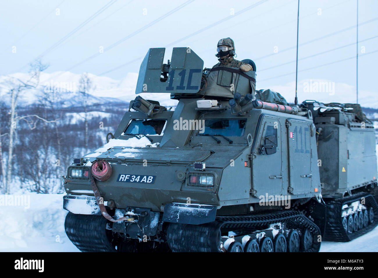 Marines mit Marine Rotational Force-Europe ein Viking belted Fahrzeug (BvS 10) eine Gruppe für eine bergige Angriff auf feindliche Position während der Bereich Ausbildung übung Teil der Übung weiß Claymore in der Nähe von Bardufoss, Norwegen, 15. Februar 2018 ein. Weiß Claymore ist einer in Großbritannien Royal Marines - LED-Training in Nordnorwegen, auf Winter Kriegsführung, einschließlich Schulung auf Bewegung im negativen Terrain und über Schnee konzentriert, und die Ausbildung in defensive und offensive Operationen bei winterlichen Bedingungen. (U.S. Marine Corps Stockfoto